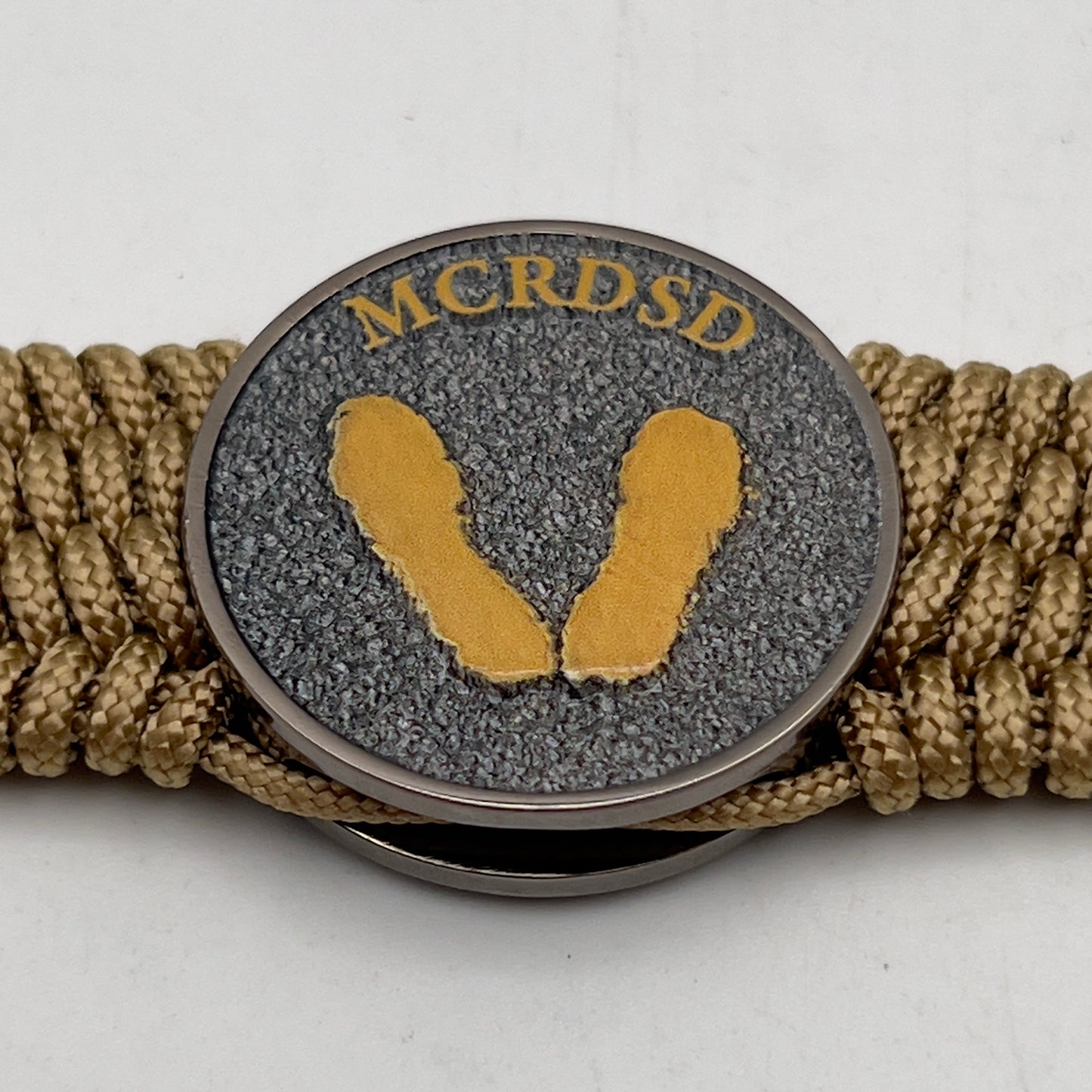 Thin, wide, flexible and comfortable braided United States Marine Corps Recruit Depot Yellow Footprints bracelet featuring a black nickel plated UV enamel painted medallion replica of an actual set of USMC footprints, a gold Cobra style tactical buckle and woven with gold Type-1 paracord.
