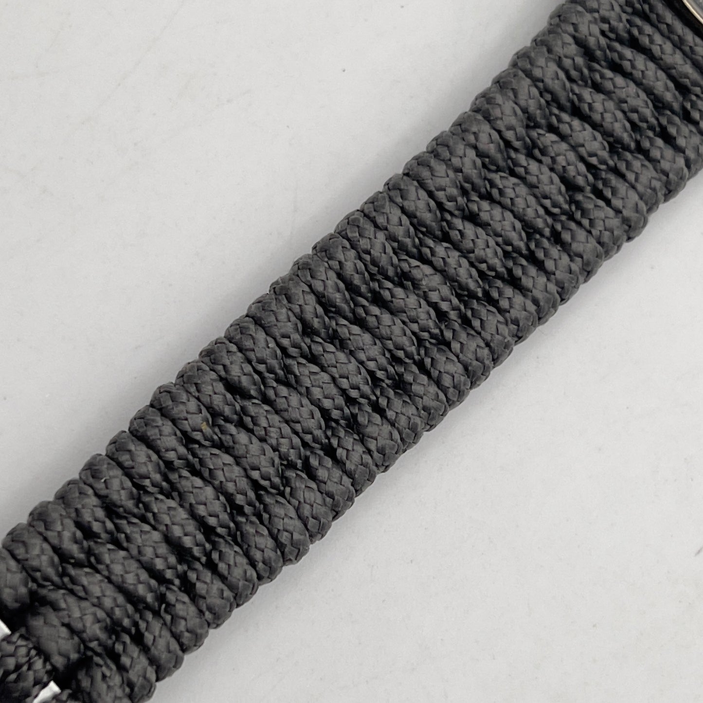 Thin, narrow, flexible and comfortable braided United States Marine Corps Recruit Depot Yellow Footprints bracelet featuring a black nickel plated UV enamel painted medallion replica of an actual set of USMC footprints, a silver Cobra style tactical buckle and woven with Charcoal Gray Type-1 paracord.