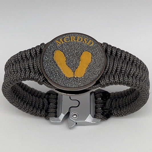 Thin, narrow, flexible and comfortable braided United States Marine Corps Recruit Depot Yellow Footprints bracelet featuring a black nickel plated UV enamel painted medallion replica of an actual set of USMC footprints, a silver Cobra style tactical buckle and woven with Charcoal Gray Type-1 paracord.