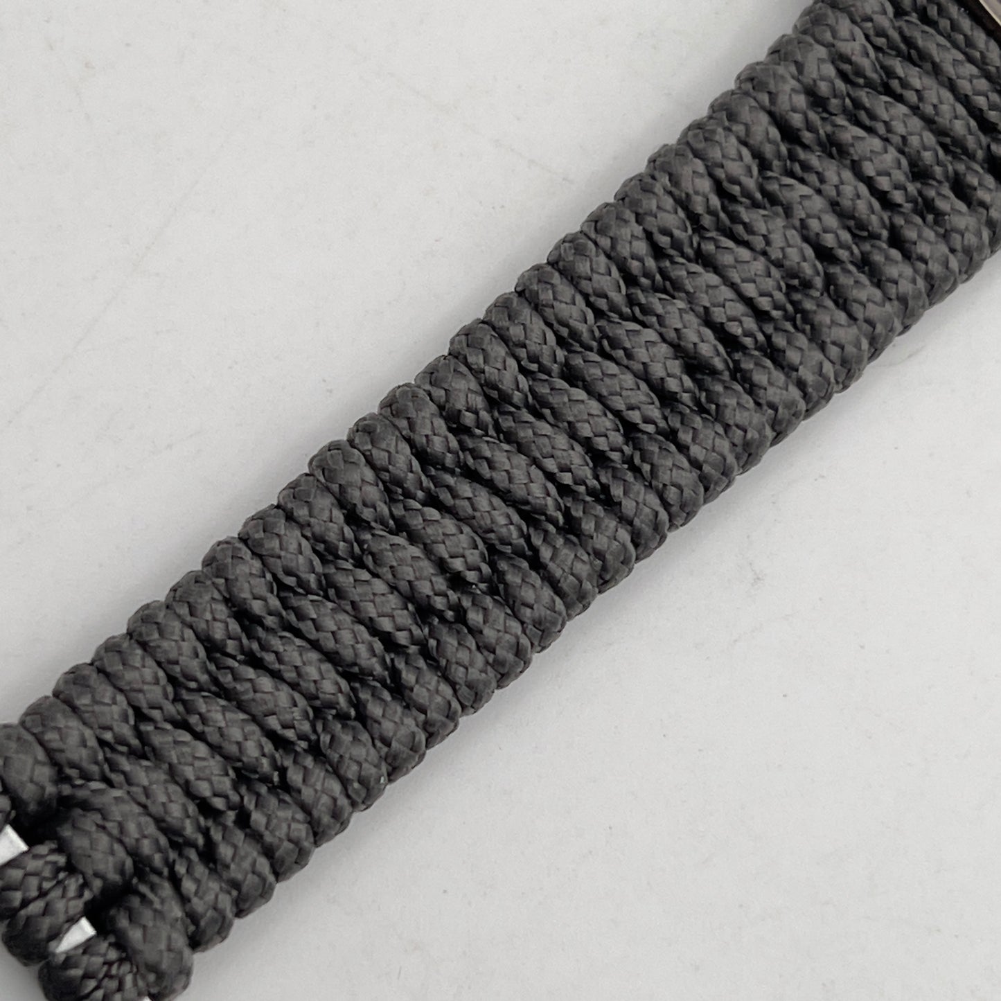 Thin, narrow, flexible and comfortable braided United States Marine Corps Recruit Depot Yellow Footprints bracelet featuring a black nickel plated UV enamel painted medallion replica of an actual set of USMC footprints, a silver Cobra style tactical buckle and woven with Charcoal Gray Type-1 paracord.