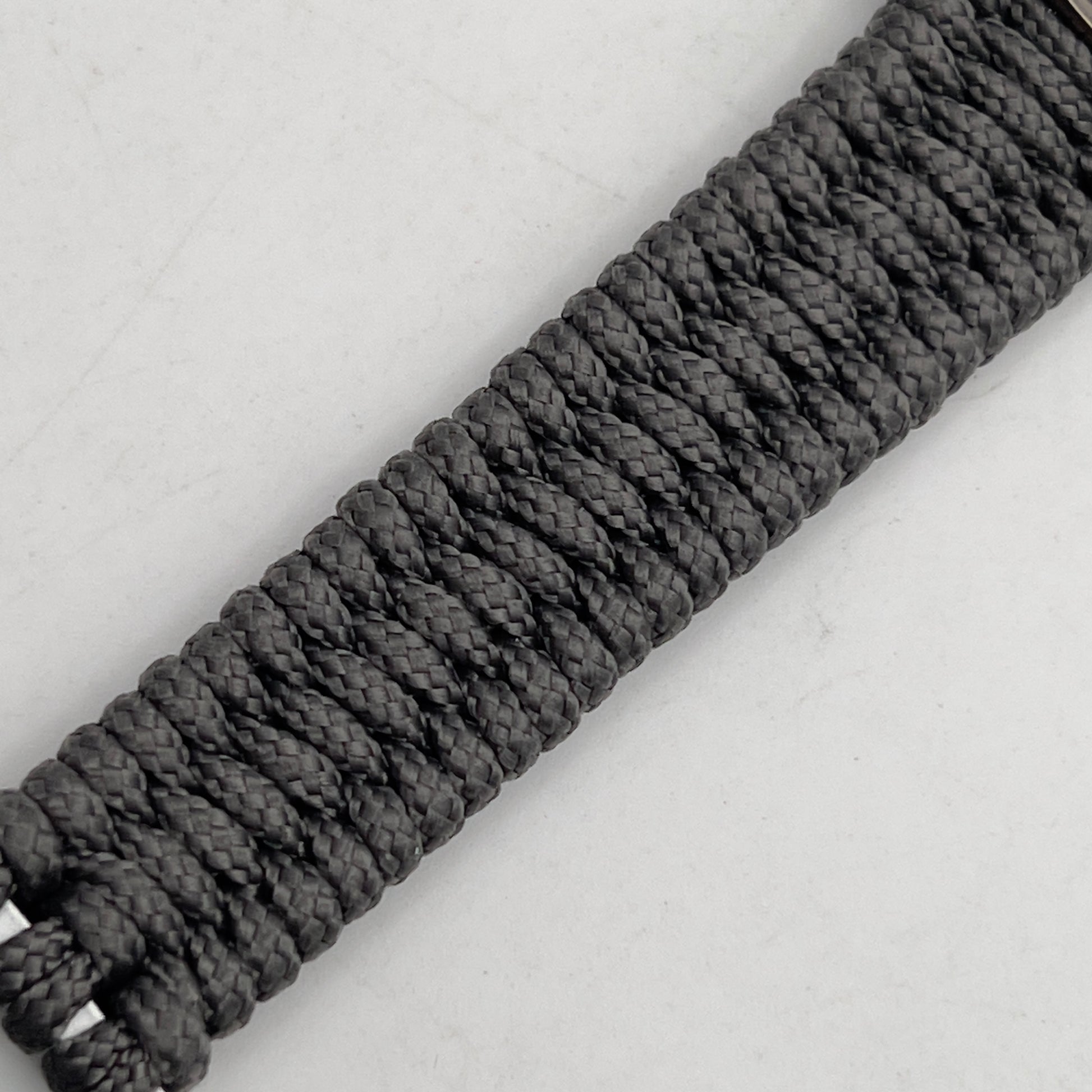 Thin, narrow, flexible and comfortable braided United States Marine Corps Recruit Depot Yellow Footprints bracelet featuring a black nickel plated UV enamel painted medallion replica of an actual set of USMC footprints, a silver Cobra style tactical buckle and woven with Charcoal Gray Type-1 paracord.