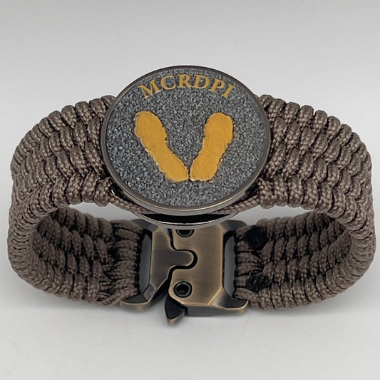 Thin, wide, flexible and comfortable braided United States Marine Corps Recruit Depot Yellow Footprints bracelet featuring a black nickel plated UV enamel painted medallion replica of an actual set of USMC recruit depot footprints, a gold Cobra style tactical buckle and woven with tan Type-1 paracord.