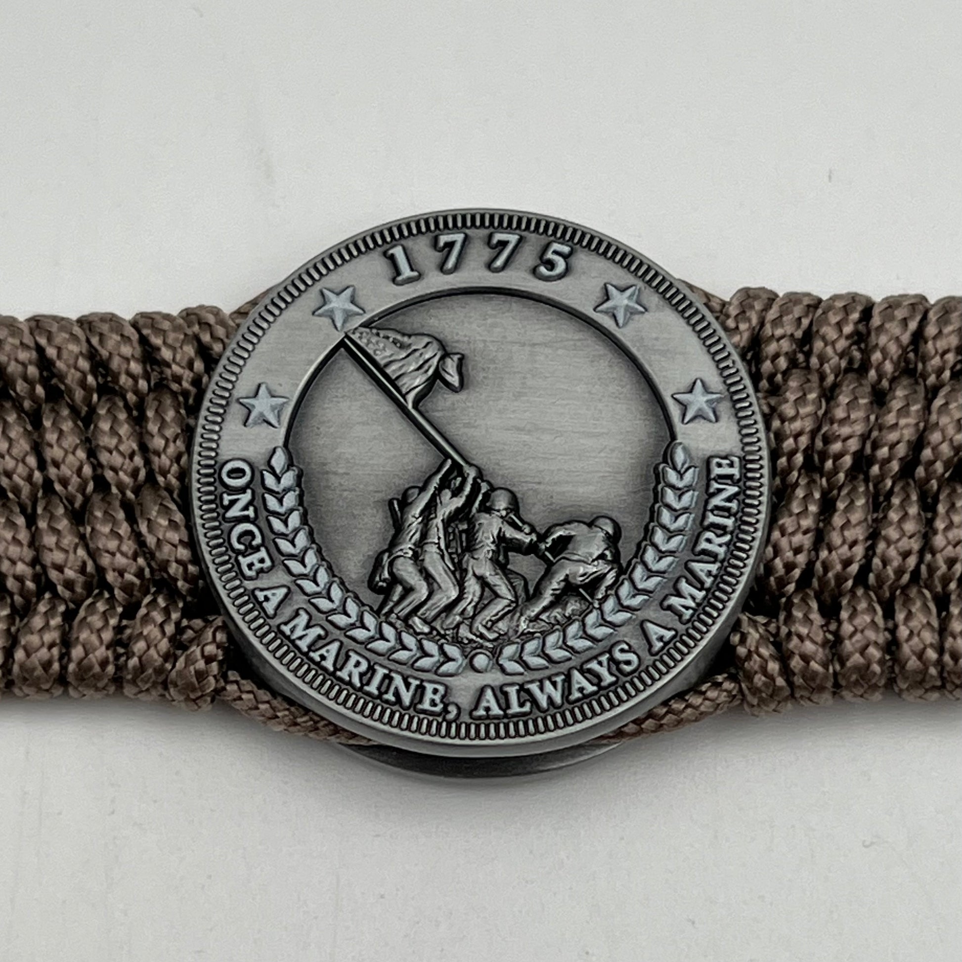 Thin, wide, flexible and comfortable braided United States Marine Corps Iwo Jima bracelet featuring an antique silver plated Iwo Jima flag raising medallion, a silver Cobra style tactical buckle and woven with tan type-1 paracord.