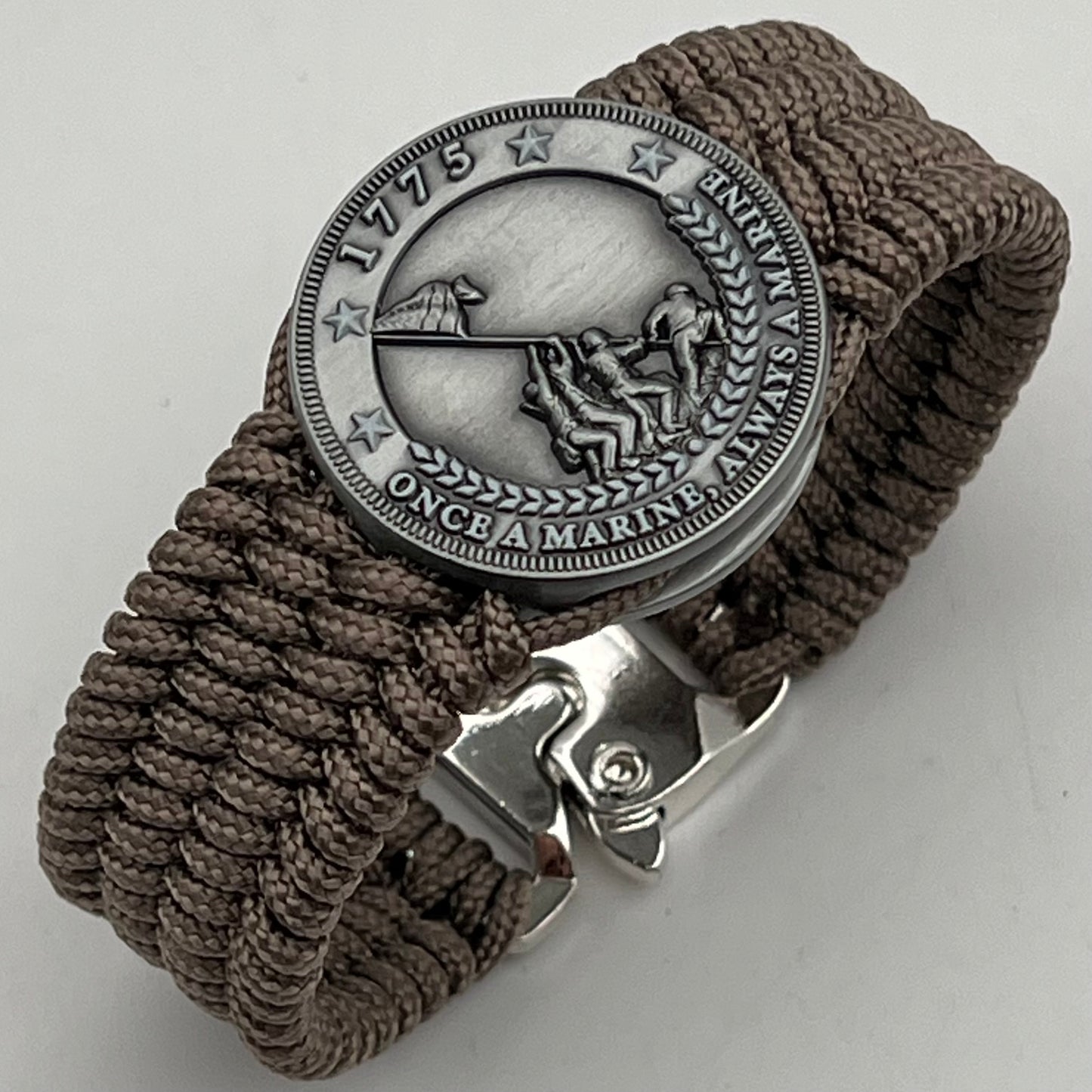 Thin, wide, flexible and comfortable braided United States Marine Corps Iwo Jima bracelet featuring an antique silver plated Iwo Jima flag raising medallion, a silver Cobra style tactical buckle and woven with tan type-1 paracord.