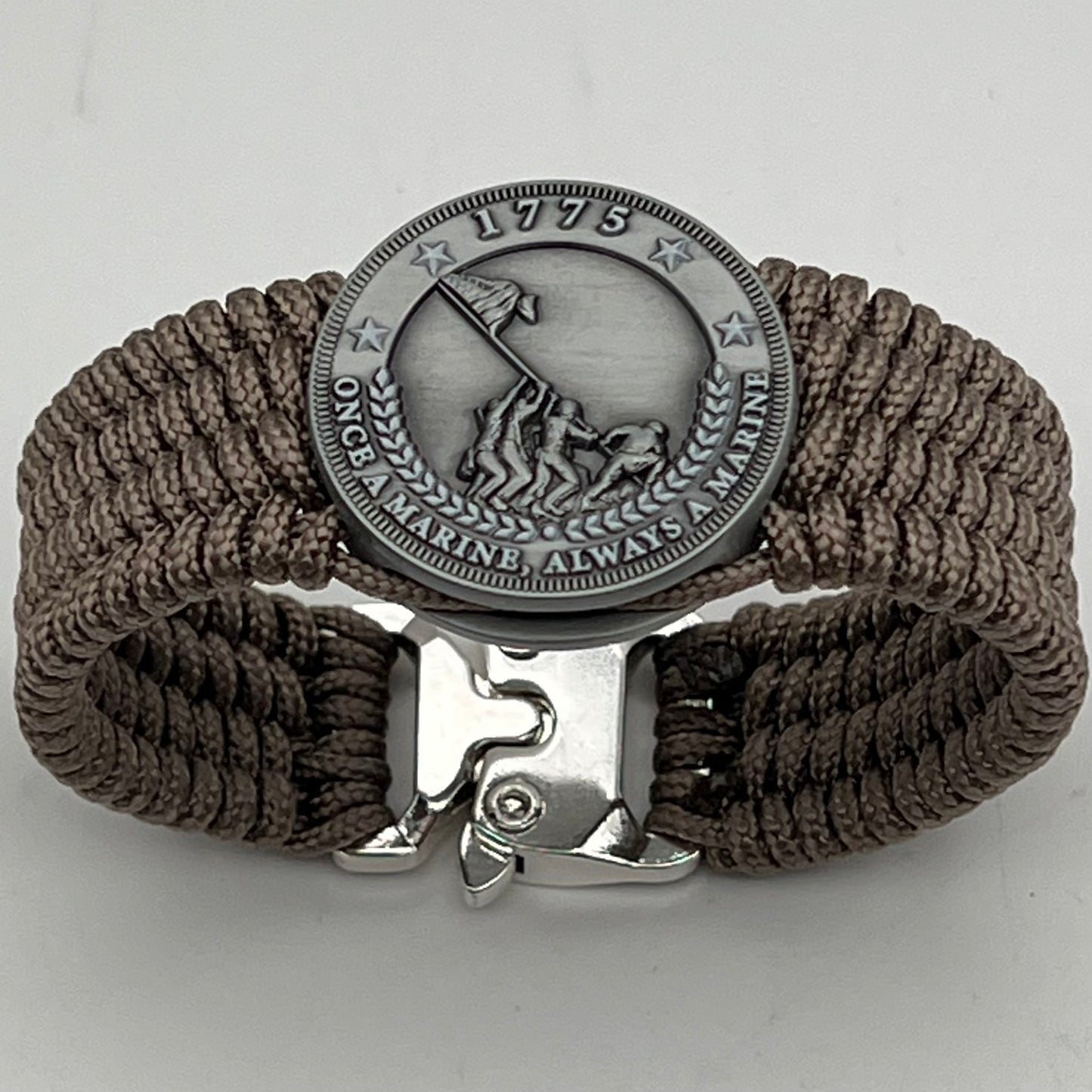 Thin, wide, flexible and comfortable braided United States Marine Corps Iwo Jima bracelet featuring an antique silver plated Iwo Jima flag raising medallion, a silver Cobra style tactical buckle and woven with tan type-1 paracord.