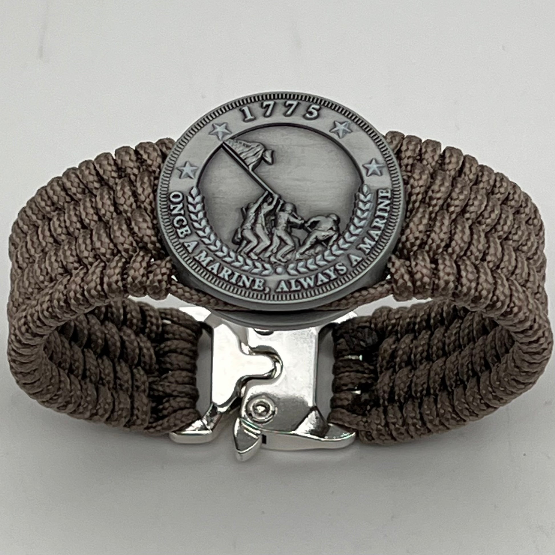 Thin, wide, flexible and comfortable braided United States Marine Corps Iwo Jima bracelet featuring an antique silver plated Iwo Jima flag raising medallion, a silver Cobra style tactical buckle and woven with tan type-1 paracord.