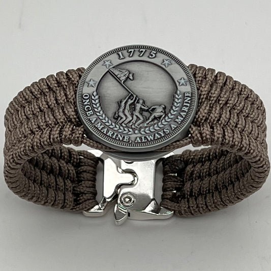Thin, wide, flexible and comfortable braided United States Marine Corps Iwo Jima bracelet featuring an antique silver plated Iwo Jima flag raising medallion, a silver Cobra style tactical buckle and woven with tan type-1 paracord.