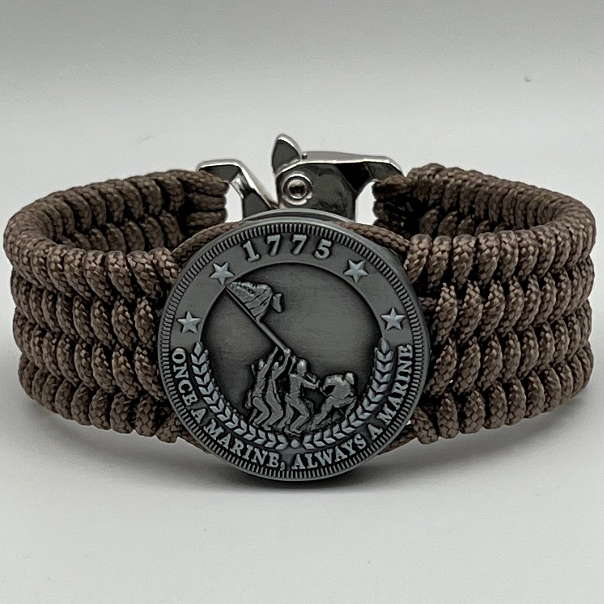 Thin, wide, flexible and comfortable braided United States Marine Corps Iwo Jima bracelet featuring an antique silver plated Iwo Jima flag raising medallion, a silver Cobra style tactical buckle and woven with tan type-1 paracord.