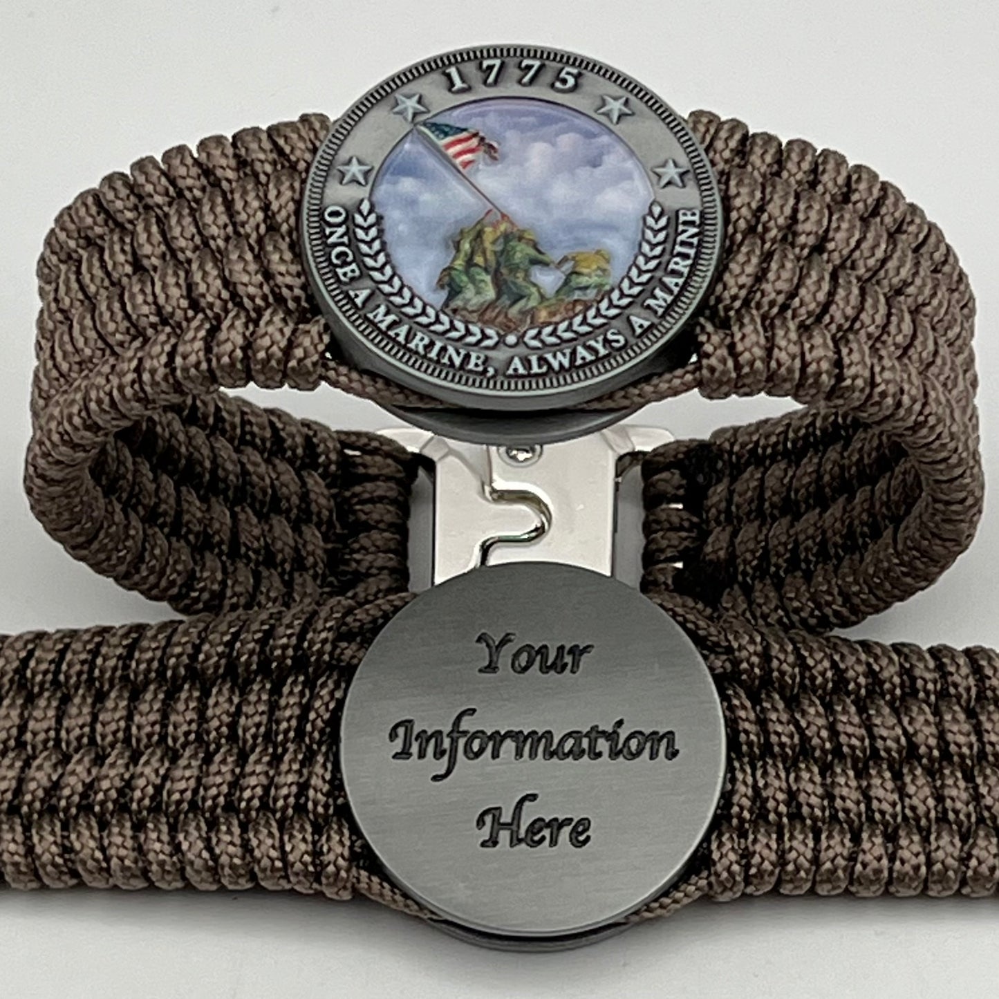 Thin, wide, flexible and comfortable braided United States Marine Corps Iwo Jima bracelet featuring an antique silver plated UV painted Iwo Jima flag raising medallion, a silver Cobra style tactical buckle and woven with tan Type-1 paracord.