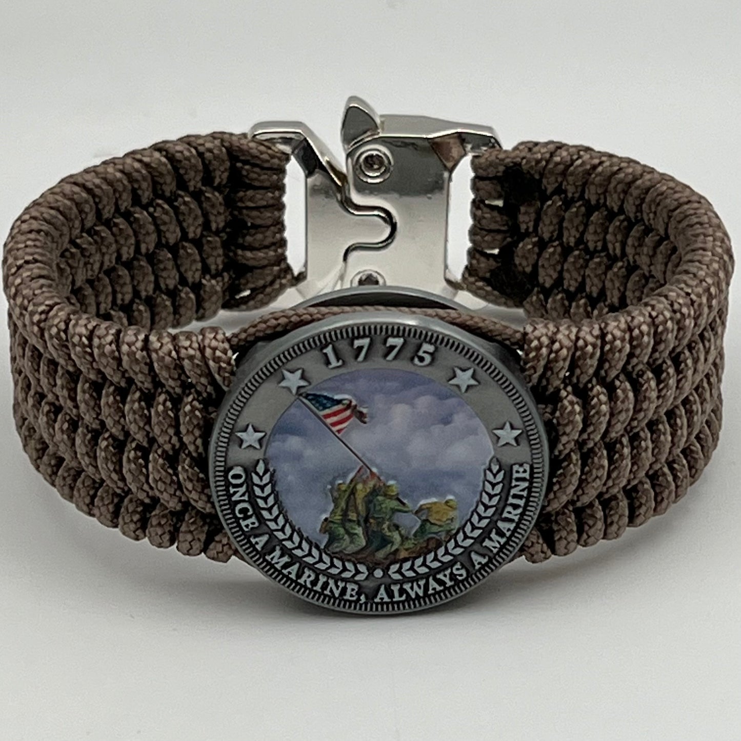Thin, wide, flexible and comfortable braided United States Marine Corps Iwo Jima bracelet featuring an antique silver plated UV painted Iwo Jima flag raising medallion, a silver Cobra style tactical buckle and woven with tan Type-1 paracord.