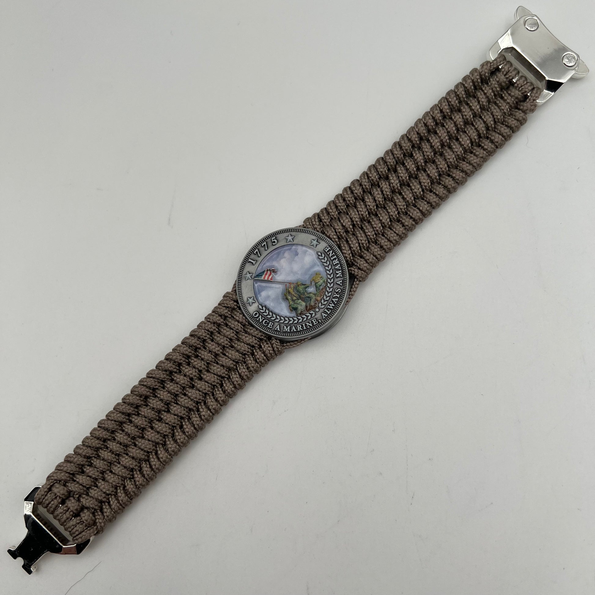 Thin, wide, flexible and comfortable braided United States Marine Corps Iwo Jima bracelet featuring an antique silver plated UV painted Iwo Jima flag raising medallion, a silver Cobra style tactical buckle and woven with tan Type-1 paracord.