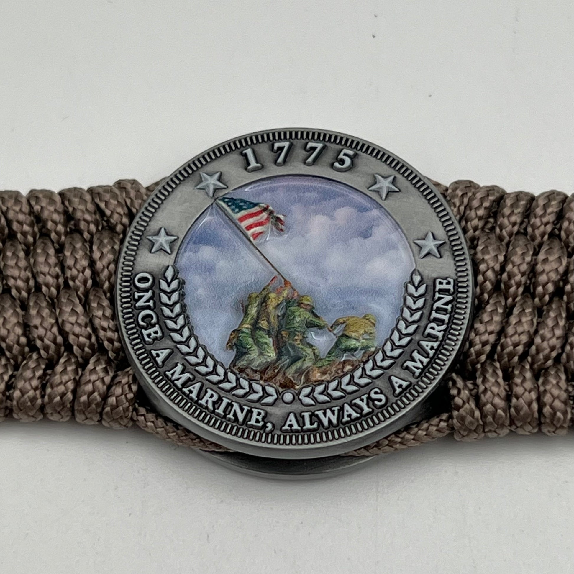 Thin, wide, flexible and comfortable braided United States Marine Corps Iwo Jima bracelet featuring an antique silver plated UV painted Iwo Jima flag raising medallion, a silver Cobra style tactical buckle and woven with tan Type-1 paracord.