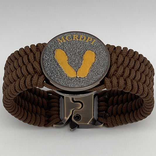 Thin, wide, flexible and comfortable braided United States Marine Corps Recruit Depot Yellow Footprints bracelet featuring a black nickel plated UV enamel painted medallion replica of an actual set of USMC footprints, a gold Cobra style tactical buckle and woven with Coyote Brown Type-1 paracord.
