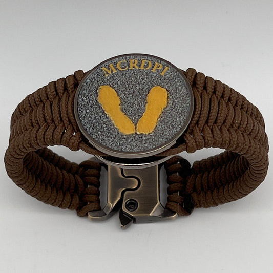 Thin, narrow, flexible and comfortable braided United States Marine Corps Recruit Depot Yellow Footprints bracelet featuring a black nickel plated UV enamel painted medallion replica of an actual set of USMC recruit depot footprints, a gold Cobra style tactical buckle and woven with Coyote Brown type-1 paracord.