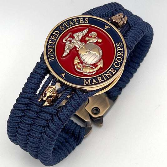 Thin, medium width, flexible and comfortable braided United States Marine Corps bracelet featuring a 24K gold and silver plated USMC officer Eagle Globe and Anchor medallion, two brass Spartan helmets, a gold Cobra style tactical buckle and woven with Navy Blue type-1 paracord.