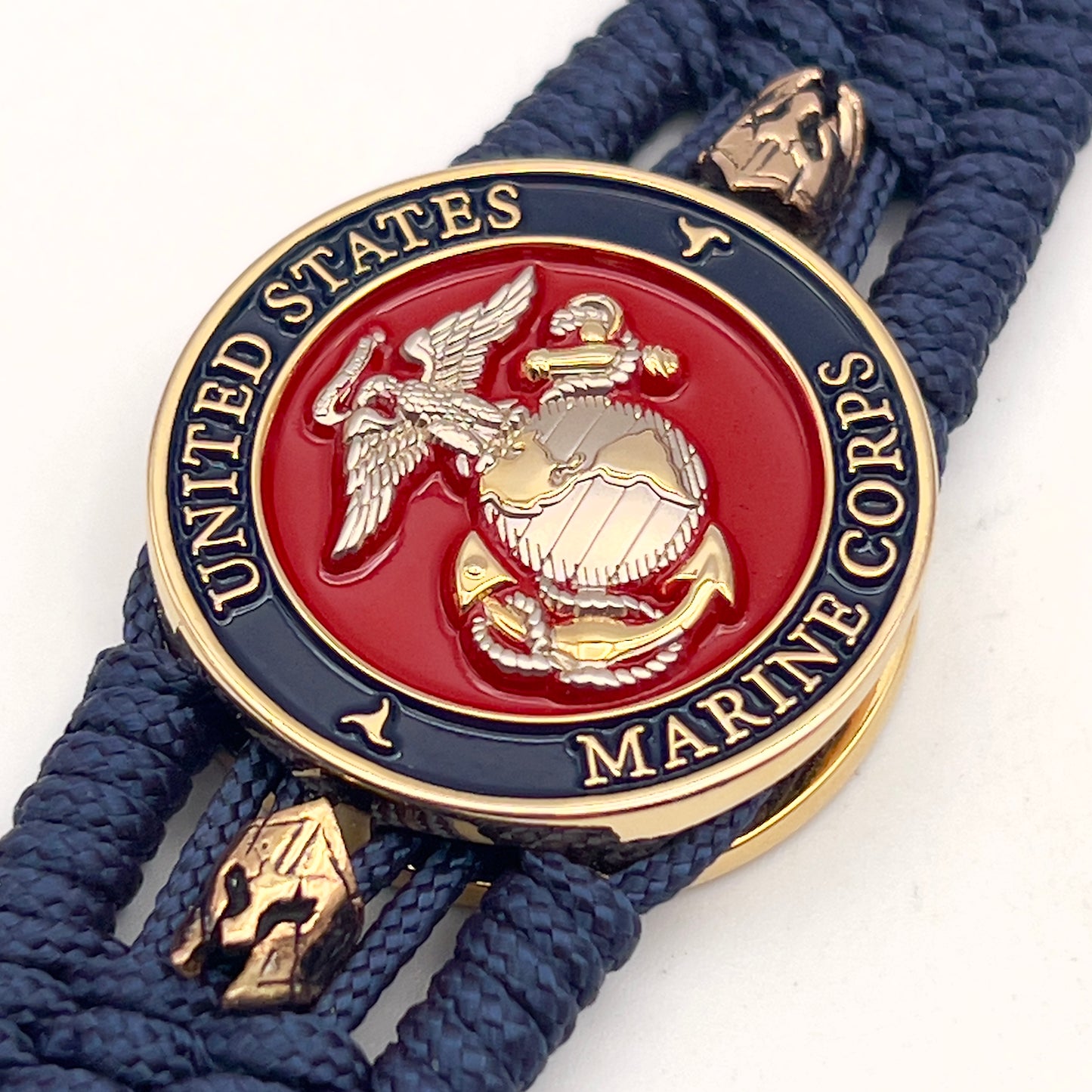 Thin, medium width, flexible and comfortable braided United States Marine Corps bracelet featuring a 24K gold and silver plated USMC officer Eagle Globe and Anchor medallion, two brass Spartan helmets, a gold Cobra style tactical buckle and woven with Navy Blue type-1 paracord.