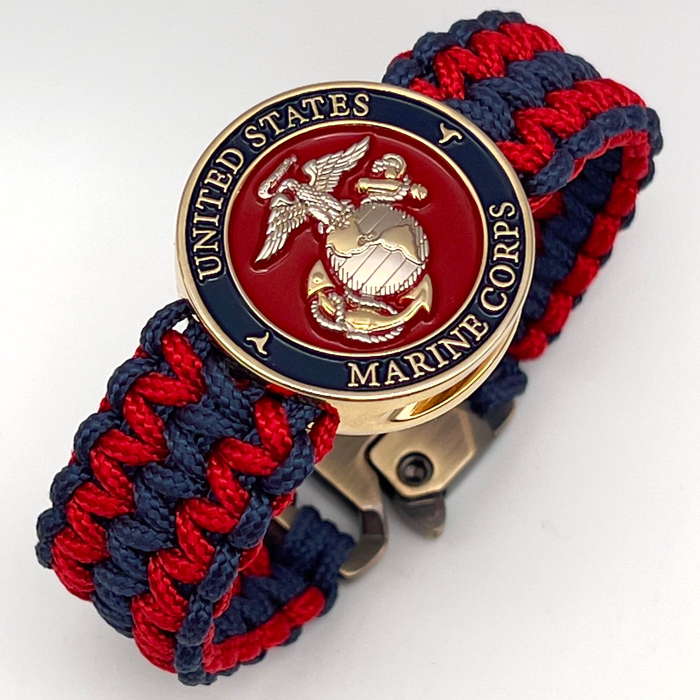 Thin, medium width, flexible and comfortable braided United States Marine Corps bracelet featuring a 24K gold and silver plated USMC officer Eagle Globe and Anchor medallion, a gold Cobra style tactical buckle and woven with Navy Blue and Imperial Red type-1 paracord.