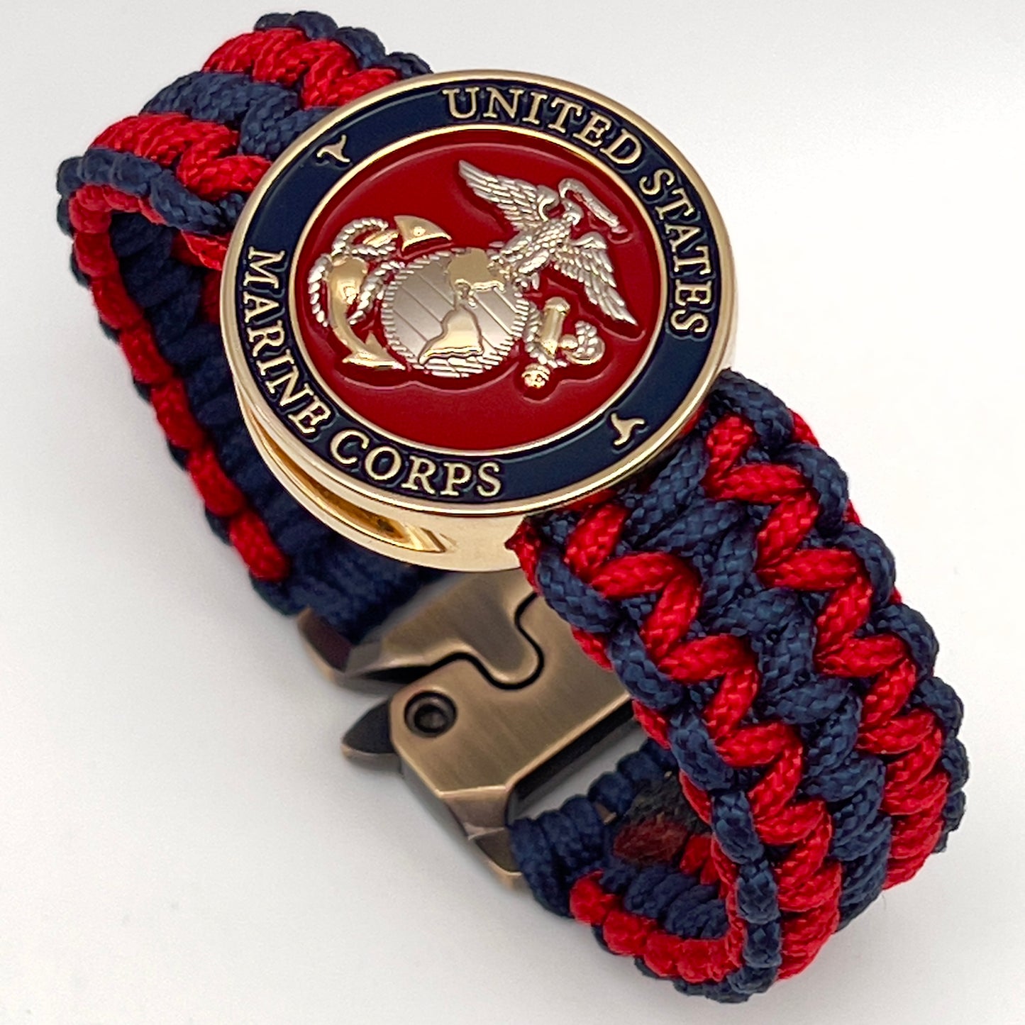 Thin, medium width, flexible and comfortable braided United States Marine Corps bracelet featuring a 24K gold and silver plated USMC officer Eagle Globe and Anchor medallion, a gold Cobra style tactical buckle and woven with Navy Blue and Imperial Red type-1 paracord.
