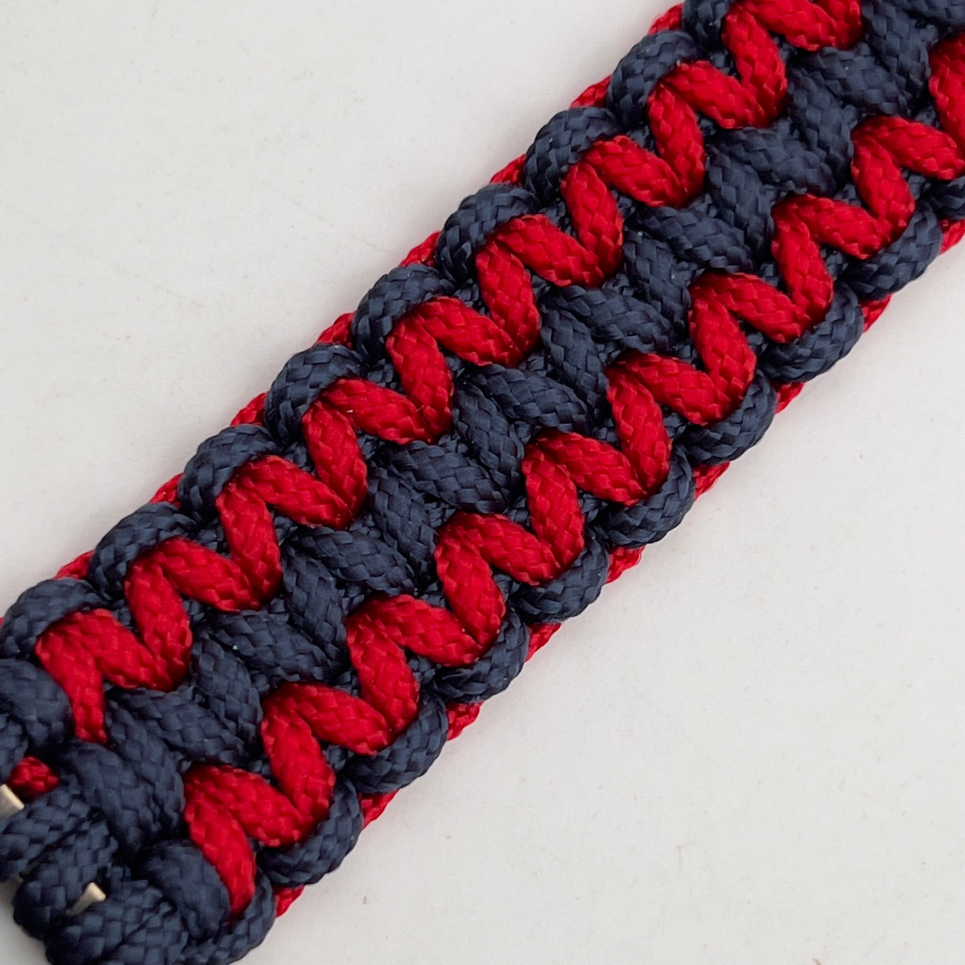 Thin, medium width, flexible and comfortable braided United States Marine Corps bracelet featuring a 24K gold and silver plated USMC officer Eagle Globe and Anchor medallion, a gold Cobra style tactical buckle and woven with Navy Blue and Imperial Red type-1 paracord.