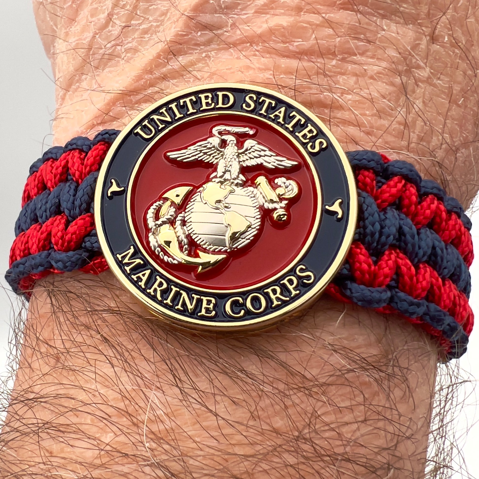 Thin, medium width, flexible and comfortable braided United States Marine Corps bracelet featuring a 24K gold and silver plated USMC officer Eagle Globe and Anchor medallion, a gold Cobra style tactical buckle and woven with Navy Blue and Imperial Red type-1 paracord.