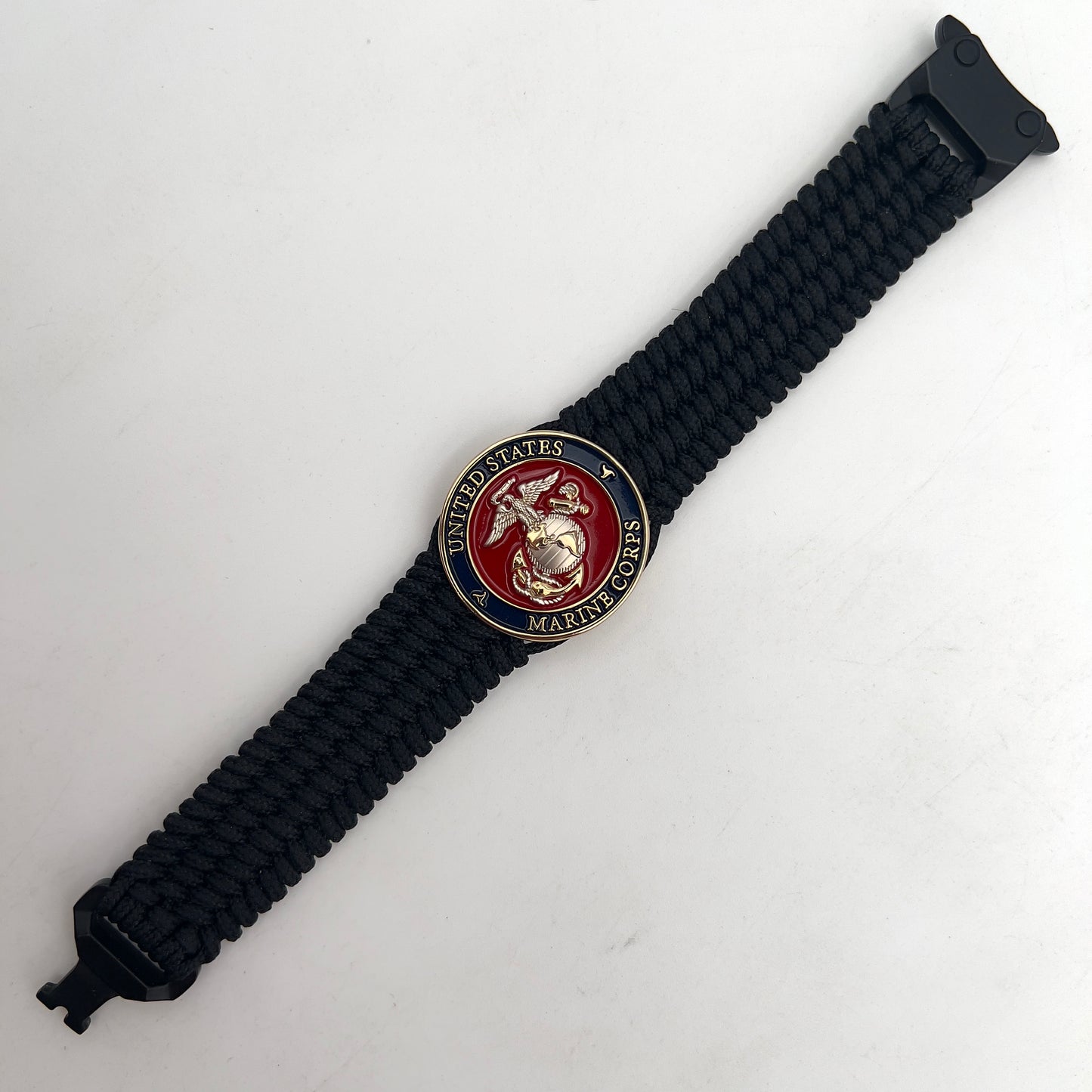 Thin, wide, flexible and comfortable braided United States Marine Corps bracelet featuring a 24K gold and silver plated USMC Eagle Globe and Anchor medallion, a black Cobra style tactical buckle and woven with black type-1 paracord.