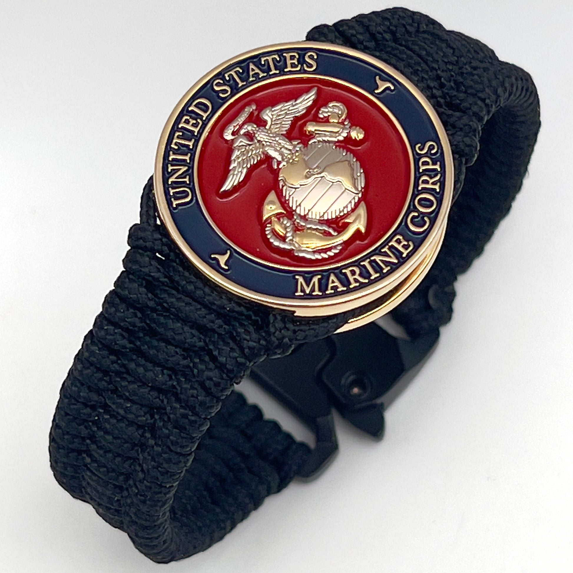 Thin, narrow, flexible and comfortable braided United States Marine Corps bracelet featuring a 24K gold and silver plated USMC Eagle Globe and Anchor medallion, a black Cobra style tactical buckle and woven with black type-1 paracord.