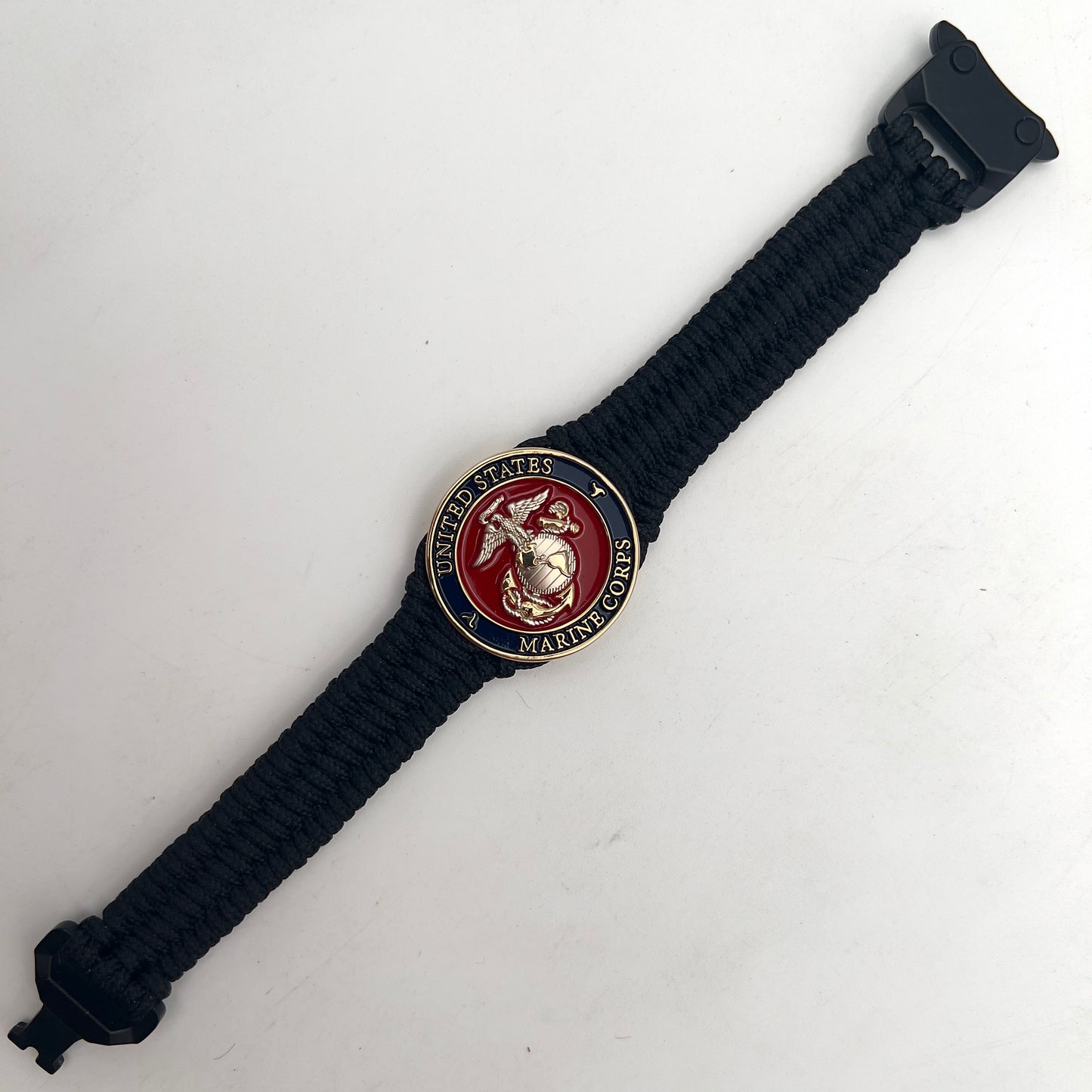 Thin, narrow, flexible and comfortable braided United States Marine Corps bracelet featuring a 24K gold and silver plated USMC Eagle Globe and Anchor medallion, a black Cobra style tactical buckle and woven with black type-1 paracord.