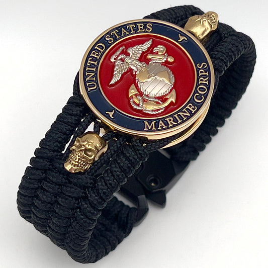 Thin, medium width, flexible and comfortable braided United States Marine Corps bracelet featuring a 24K gold and silver plated USMC officer Eagle Globe and Anchor medallion, two gold plated skulls, a black Cobra style tactical buckle and woven with black type-1 paracord.