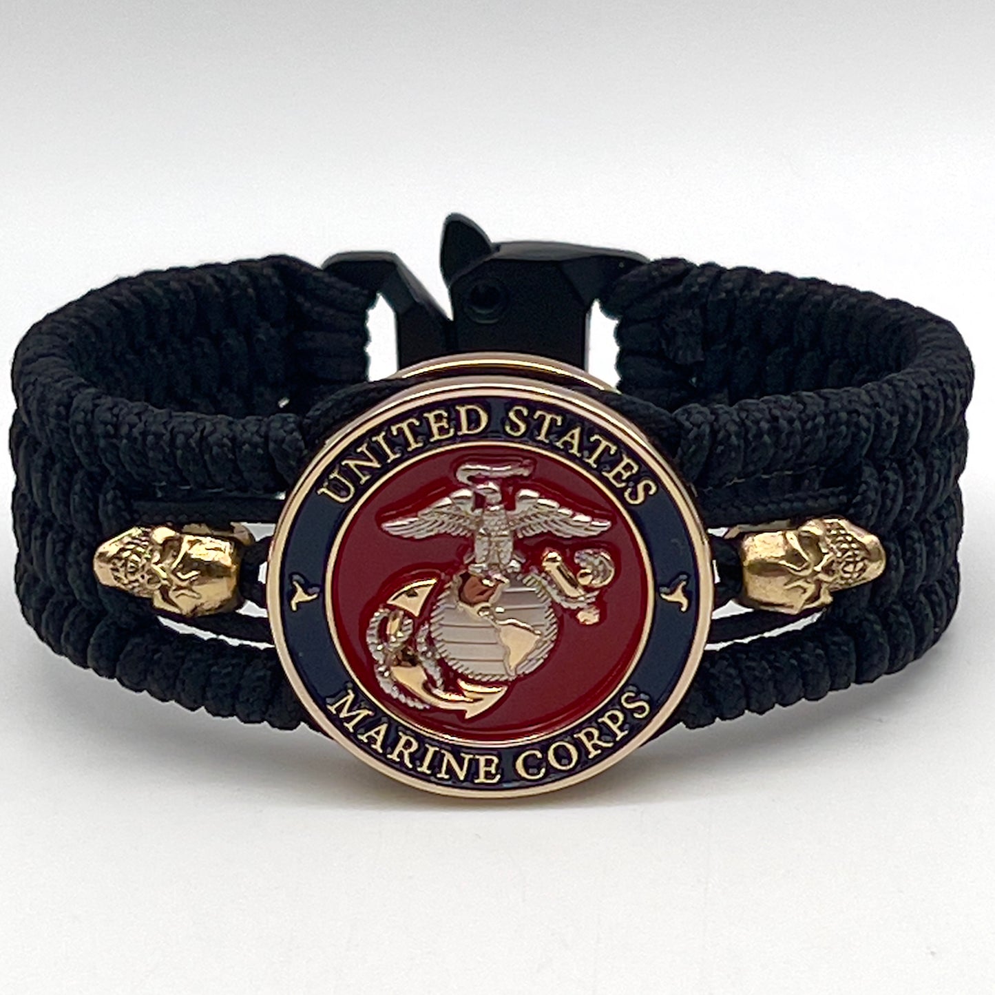 Thin, medium width, flexible and comfortable braided United States Marine Corps bracelet featuring a 24K gold and silver plated USMC officer Eagle Globe and Anchor medallion, two gold plated skulls, a black Cobra style tactical buckle and woven with black type-1 paracord.