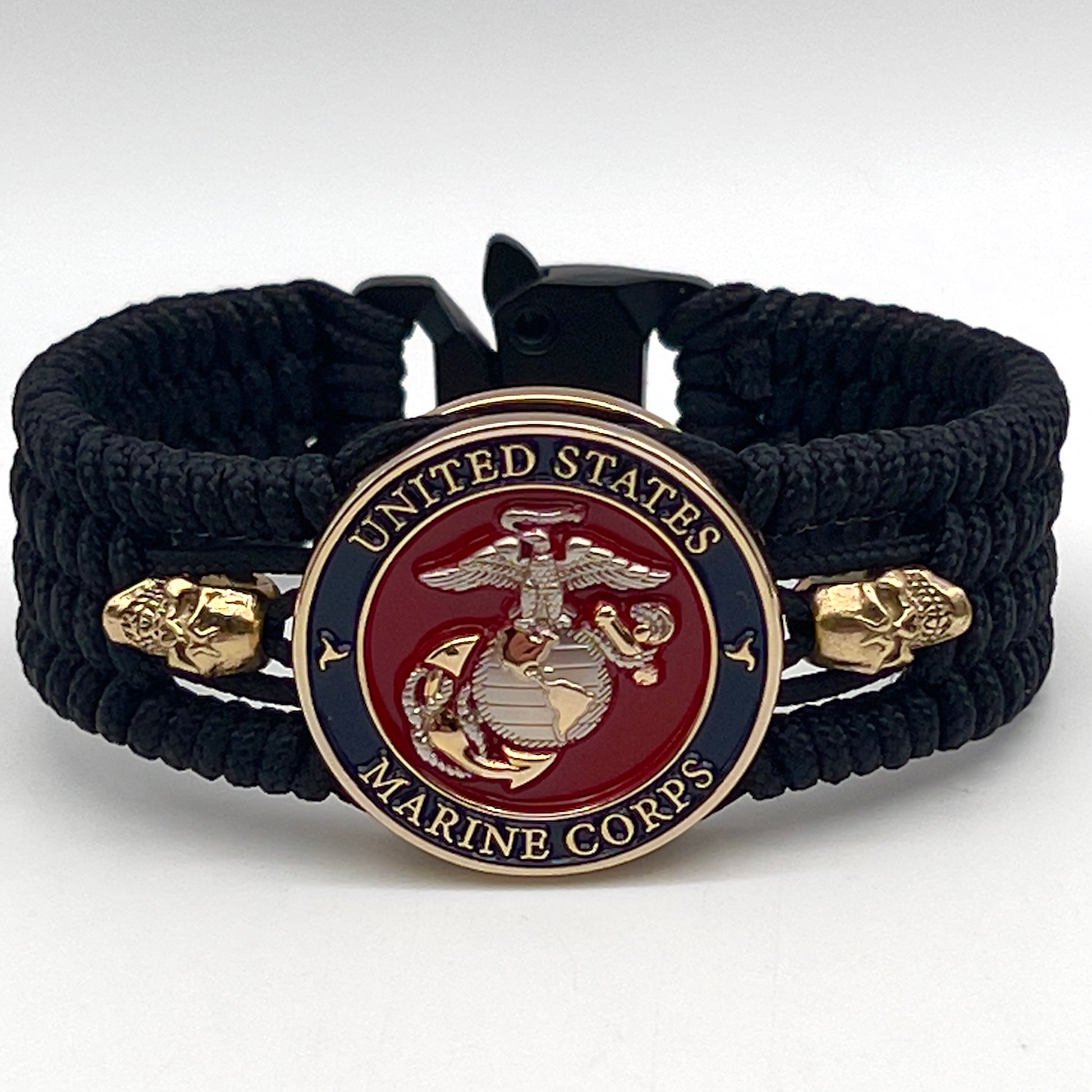 Thin, medium width, flexible and comfortable braided United States Marine Corps bracelet featuring a 24K gold and silver plated USMC officer Eagle Globe and Anchor medallion, two gold plated skulls, a black Cobra style tactical buckle and woven with black type-1 paracord.