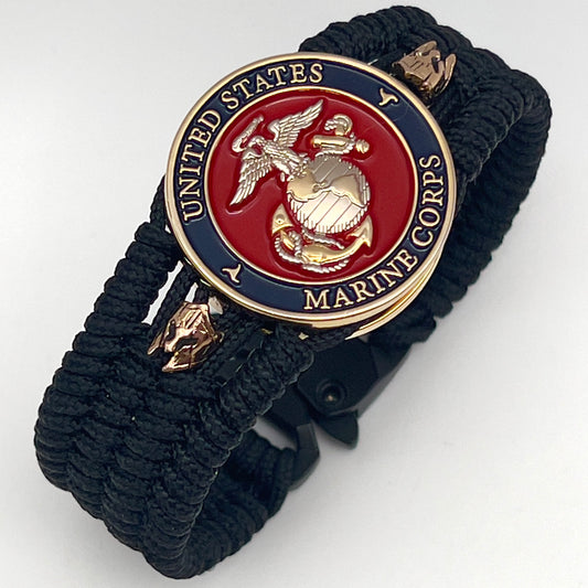 Thin, medium width, flexible and comfortable braided United States Marine Corps bracelet featuring a 24K gold and silver plated USMC officer Eagle Globe and Anchor medallion, two brass micro Spartan helmets, a black Cobra style tactical buckle and woven with black type-1 paracord.