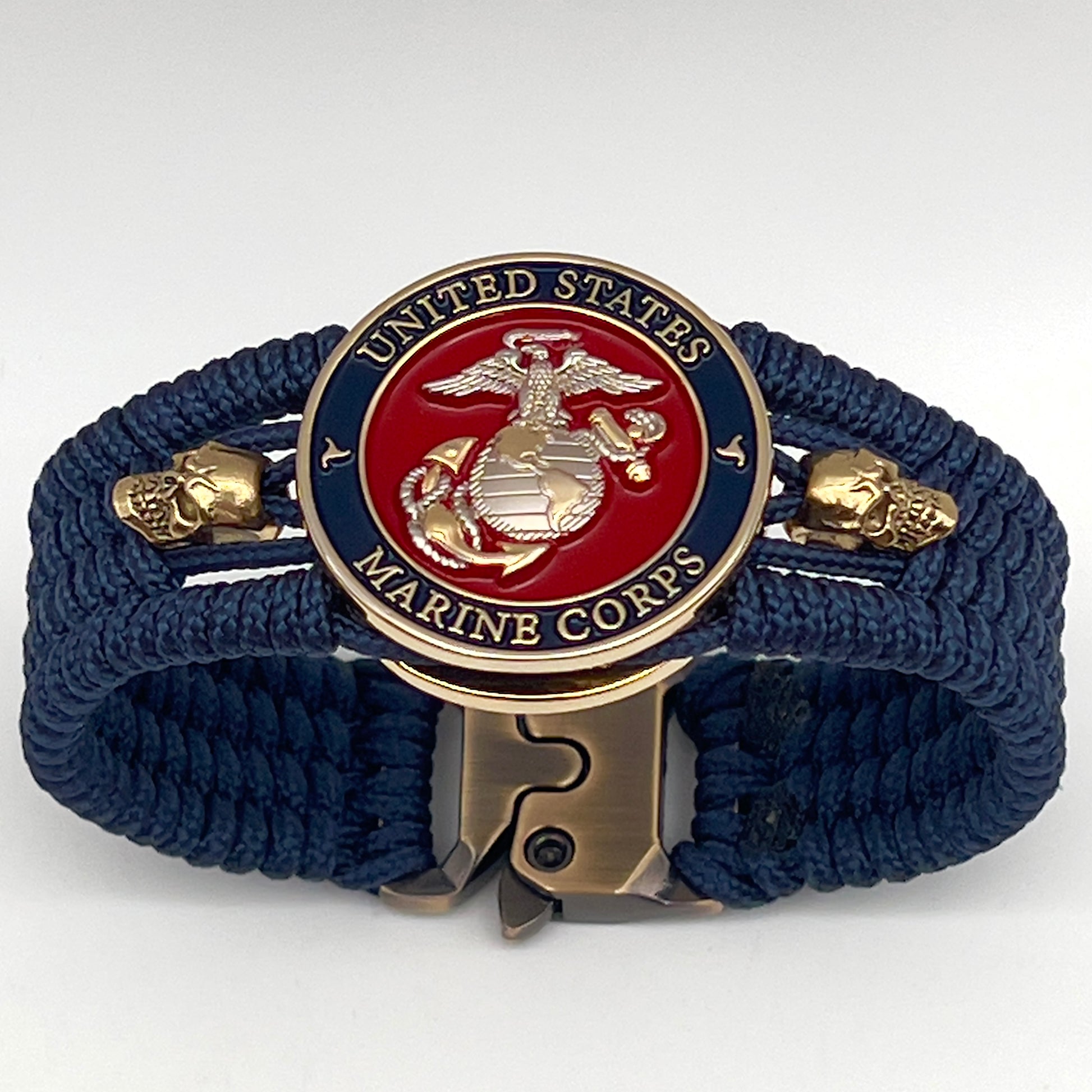 Thin, medium width, flexible and comfortable braided United States Marine Corps bracelet featuring a 24K gold and silver plated USMC officer Eagle Globe and Anchor medallion, two gold micro skulls, a gold Cobra style tactical buckle and woven with Navy blue type-1 paracord.
