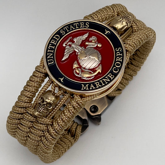 Thin, medium width, flexible and comfortable braided United States Marine Corps bracelet featuring a 24K gold and silver plated USMC officer Eagle Globe and Anchor medallion, two gold micro skulls, a gold Cobra style tactical buckle and woven with gold type-1 paracord.