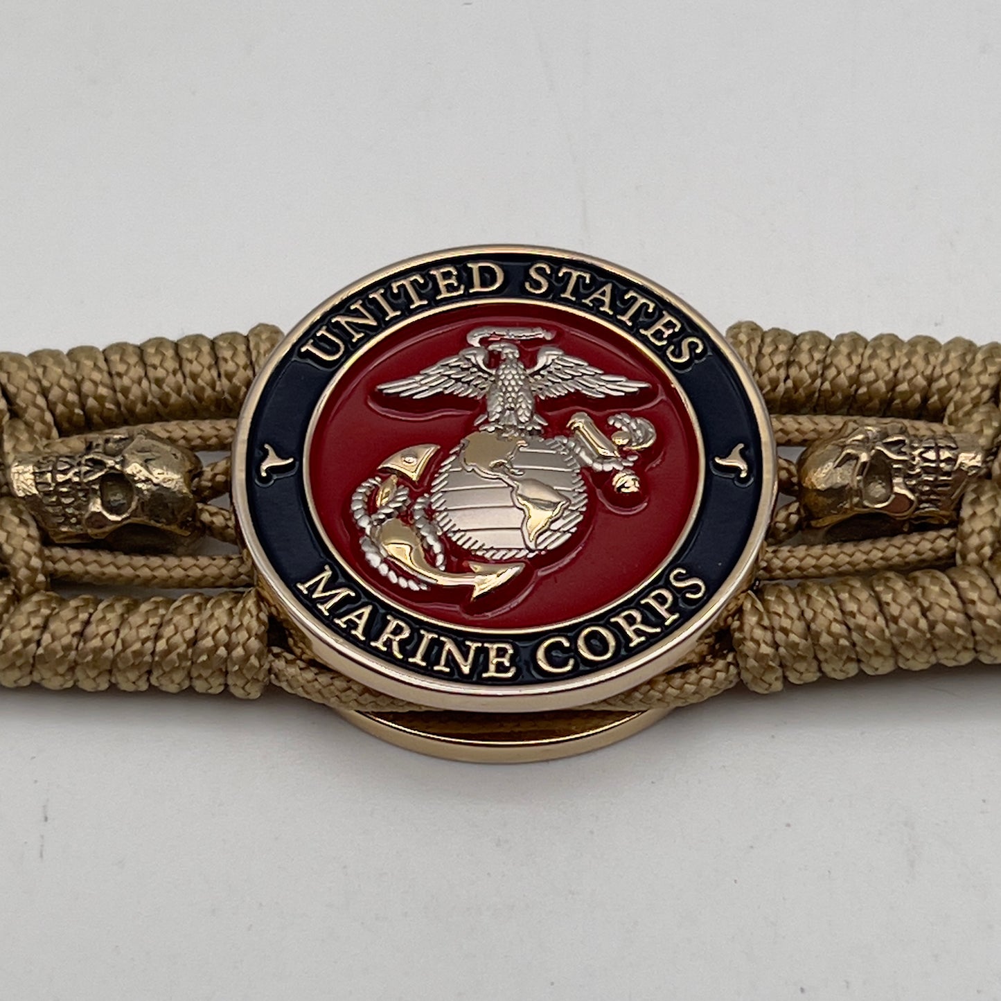 Thin, medium width, flexible and comfortable braided United States Marine Corps bracelet featuring a 24K gold and silver plated USMC officer Eagle Globe and Anchor medallion, two gold micro skulls, a gold Cobra style tactical buckle and woven with gold type-1 paracord.