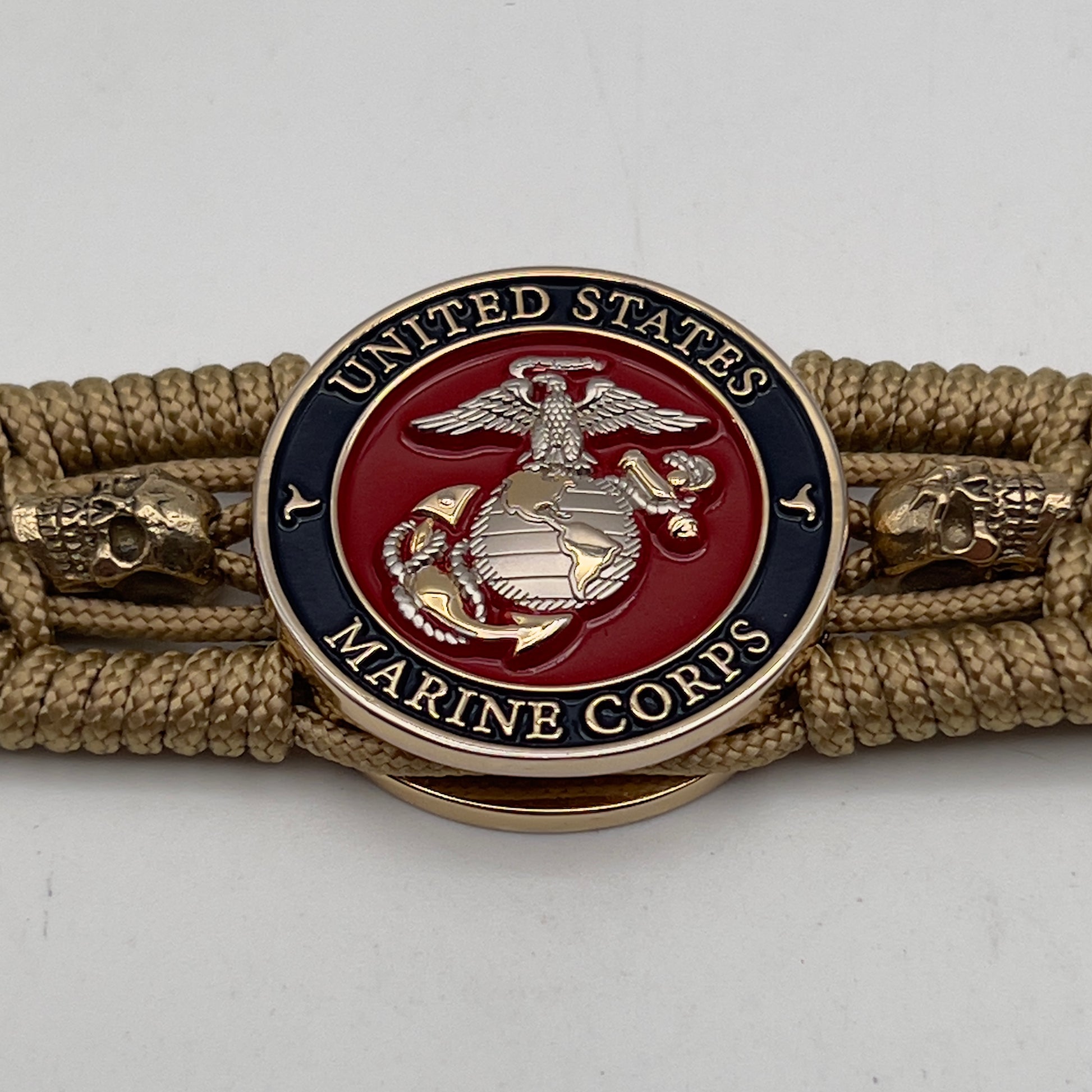 Thin, medium width, flexible and comfortable braided United States Marine Corps bracelet featuring a 24K gold and silver plated USMC officer Eagle Globe and Anchor medallion, two gold micro skulls, a gold Cobra style tactical buckle and woven with gold type-1 paracord.