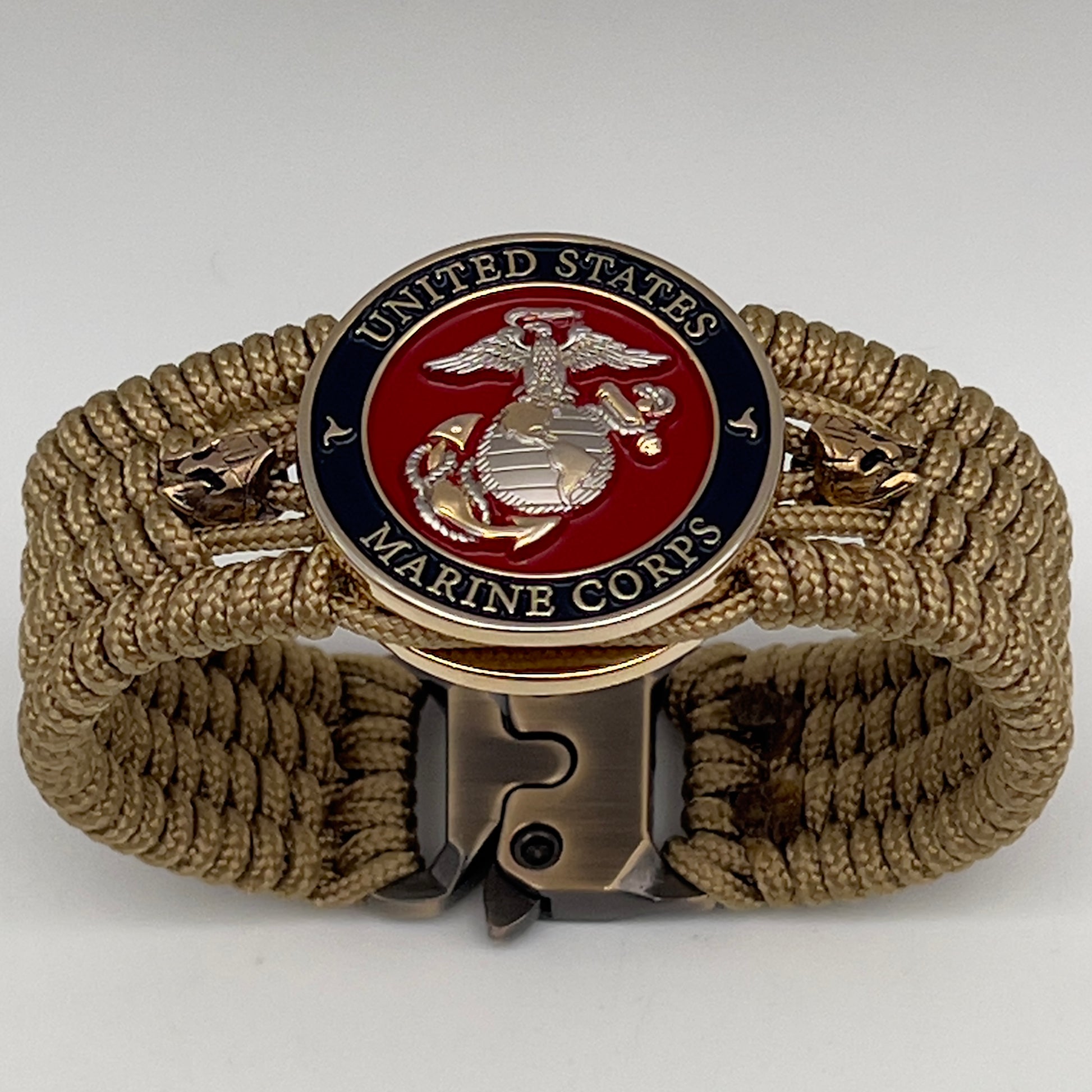 Thin, medium width, flexible and comfortable braided United States Marine Corps bracelet featuring a 24K gold and silver plated USMC officer Eagle Globe and Anchor medallion, two brass micro Spartan helmets, a gold Cobra style tactical buckle and woven with gold type-1 paracord.
