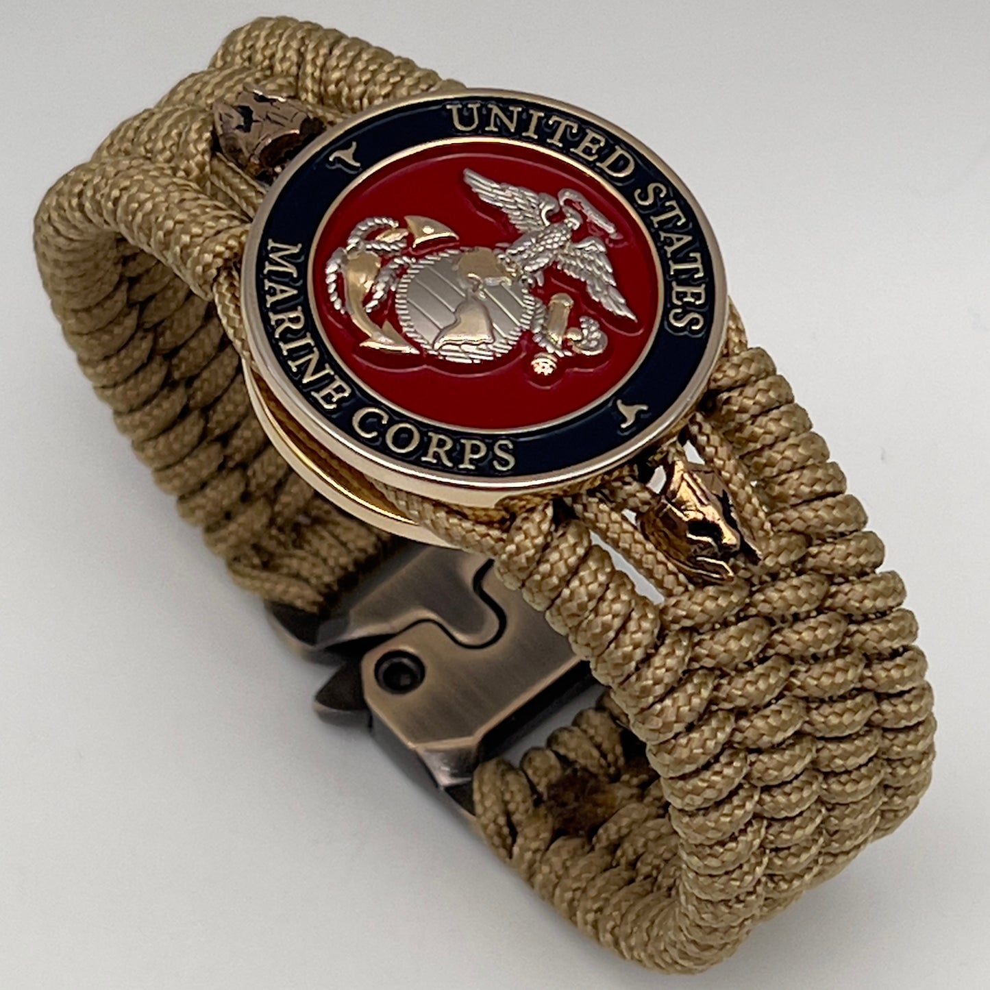 Thin, medium width, flexible and comfortable braided United States Marine Corps bracelet featuring a 24K gold and silver plated USMC officer Eagle Globe and Anchor medallion, two brass micro Spartan helmets, a gold Cobra style tactical buckle and woven with gold type-1 paracord.