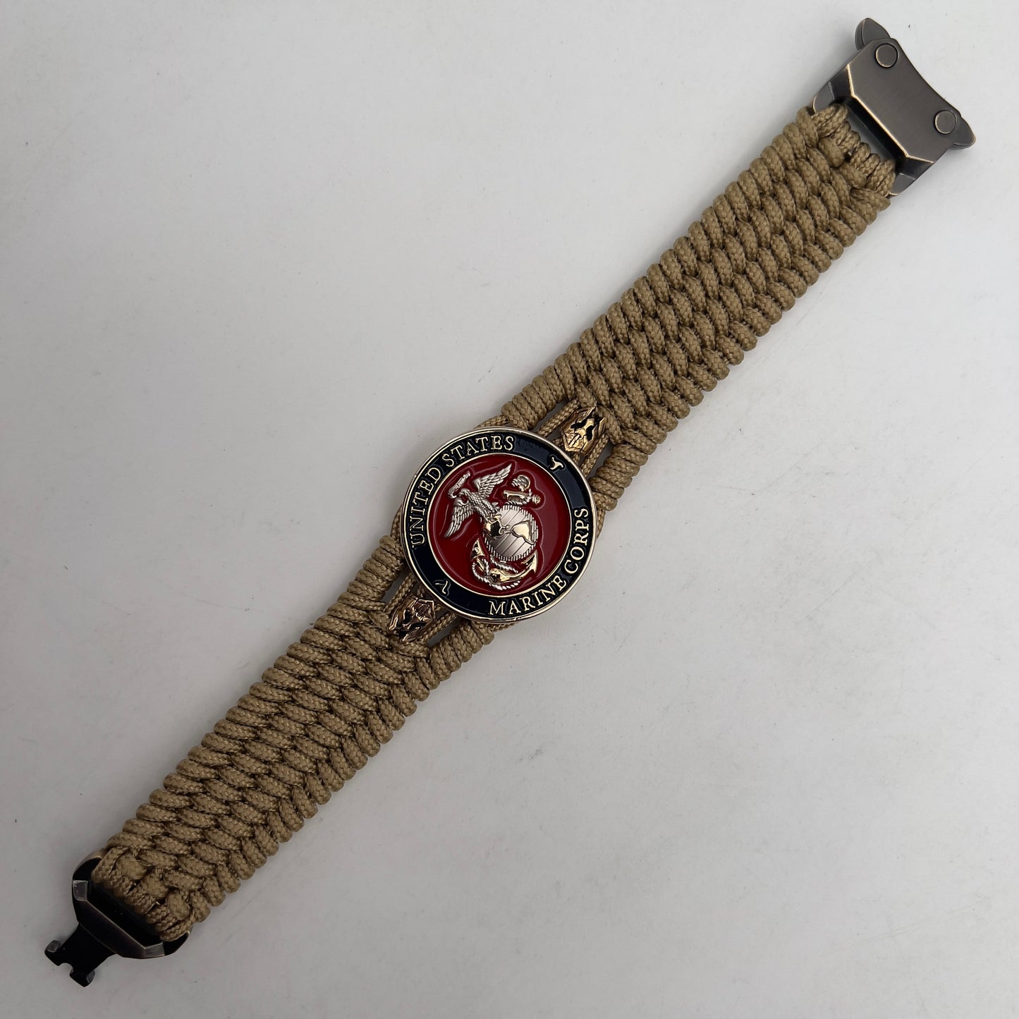 Thin, medium width, flexible and comfortable braided United States Marine Corps bracelet featuring a 24K gold and silver plated USMC officer Eagle Globe and Anchor medallion, two brass micro Spartan helmets, a gold Cobra style tactical buckle and woven with gold type-1 paracord.