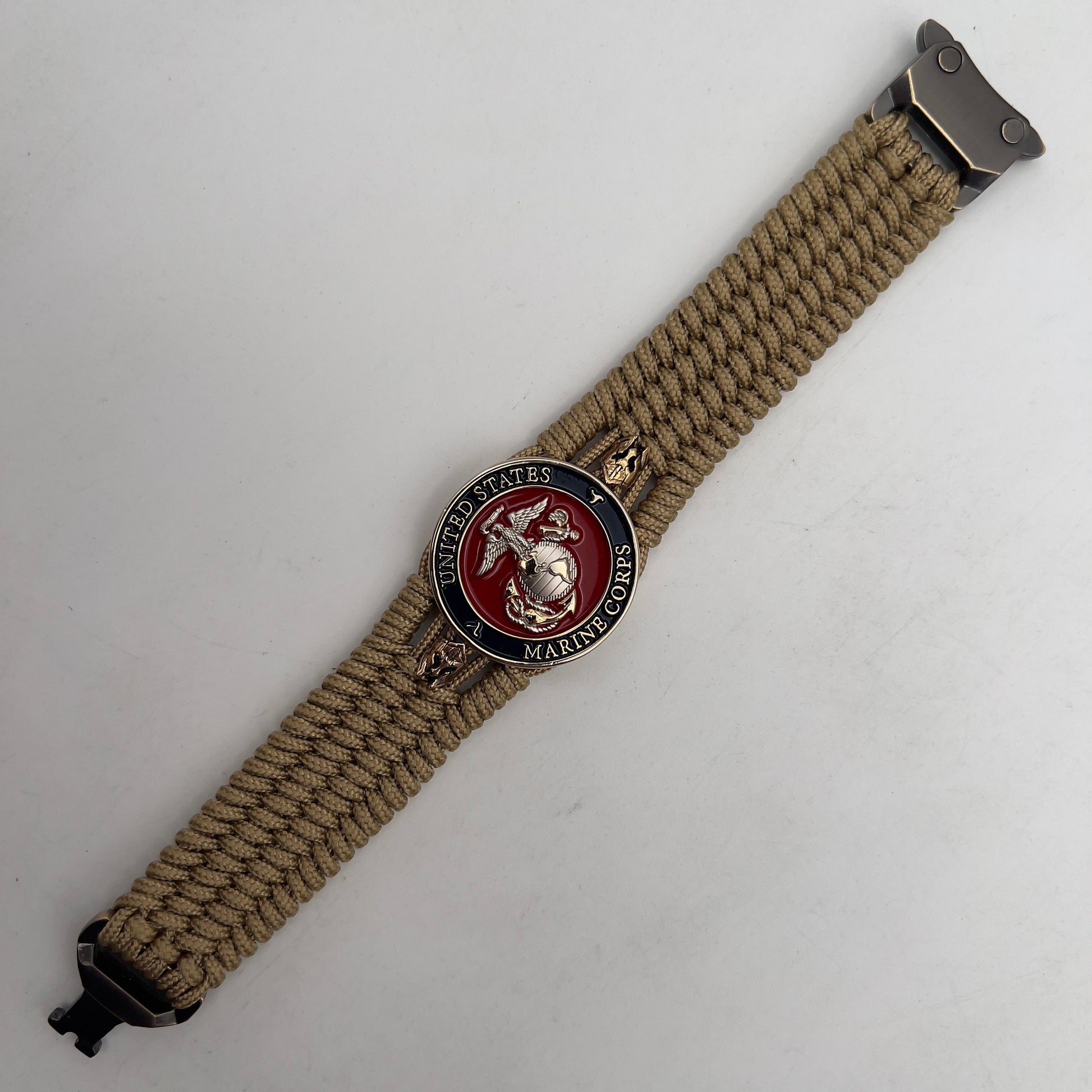 Thin, medium width, flexible and comfortable braided United States Marine Corps bracelet featuring a 24K gold and silver plated USMC officer Eagle Globe and Anchor medallion, two brass micro Spartan helmets, a gold Cobra style tactical buckle and woven with gold type-1 paracord.