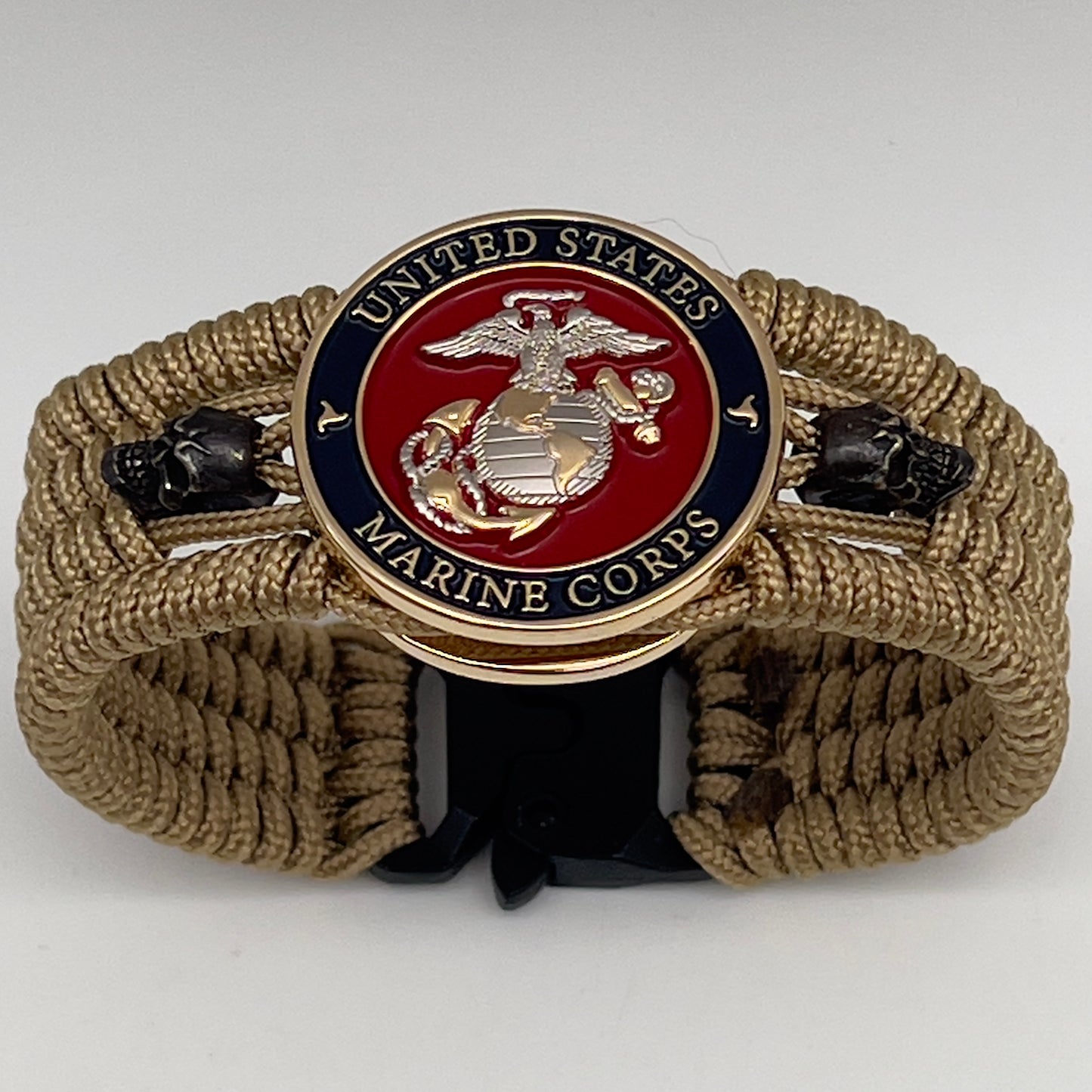 Thin, medium width, flexible and comfortable braided United States Marine Corps bracelet featuring a 24K gold and silver plated USMC officer Eagle Globe and Anchor medallion, two black micro skulls, a black Cobra style tactical buckle and woven with gold type-1 paracord.