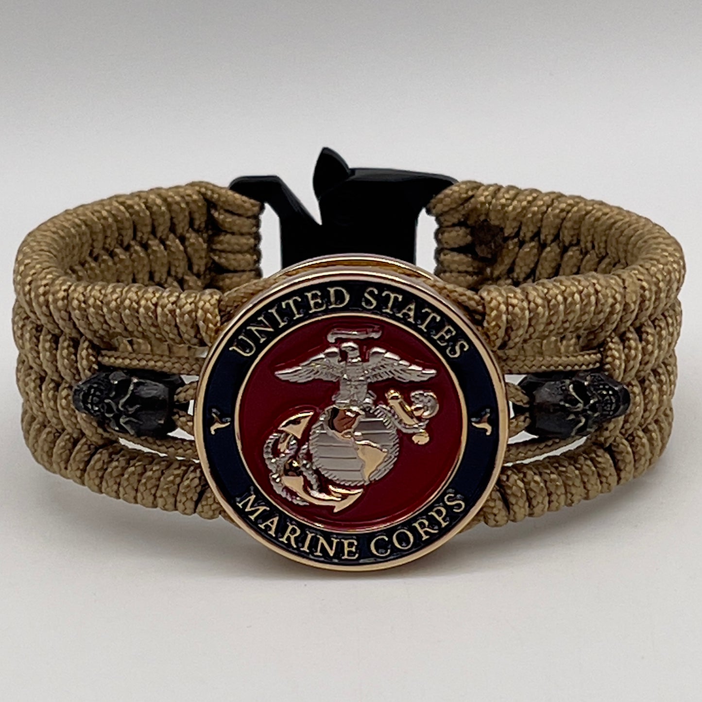 Thin, medium width, flexible and comfortable braided United States Marine Corps bracelet featuring a 24K gold and silver plated USMC officer Eagle Globe and Anchor medallion, two black micro skulls, a black Cobra style tactical buckle and woven with gold type-1 paracord.