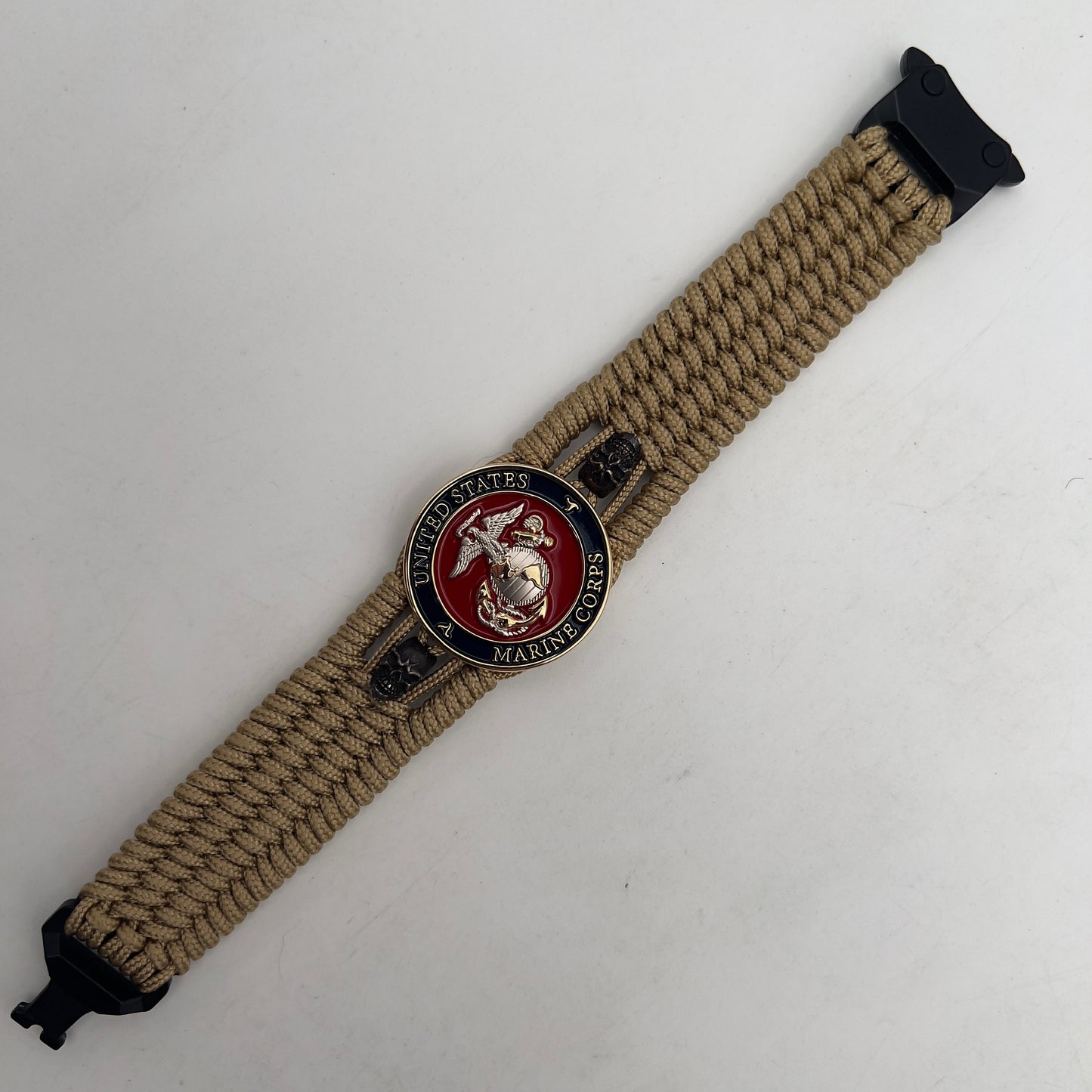 Thin, medium width, flexible and comfortable braided United States Marine Corps bracelet featuring a 24K gold and silver plated USMC officer Eagle Globe and Anchor medallion, two black micro skulls, a black Cobra style tactical buckle and woven with gold type-1 paracord.