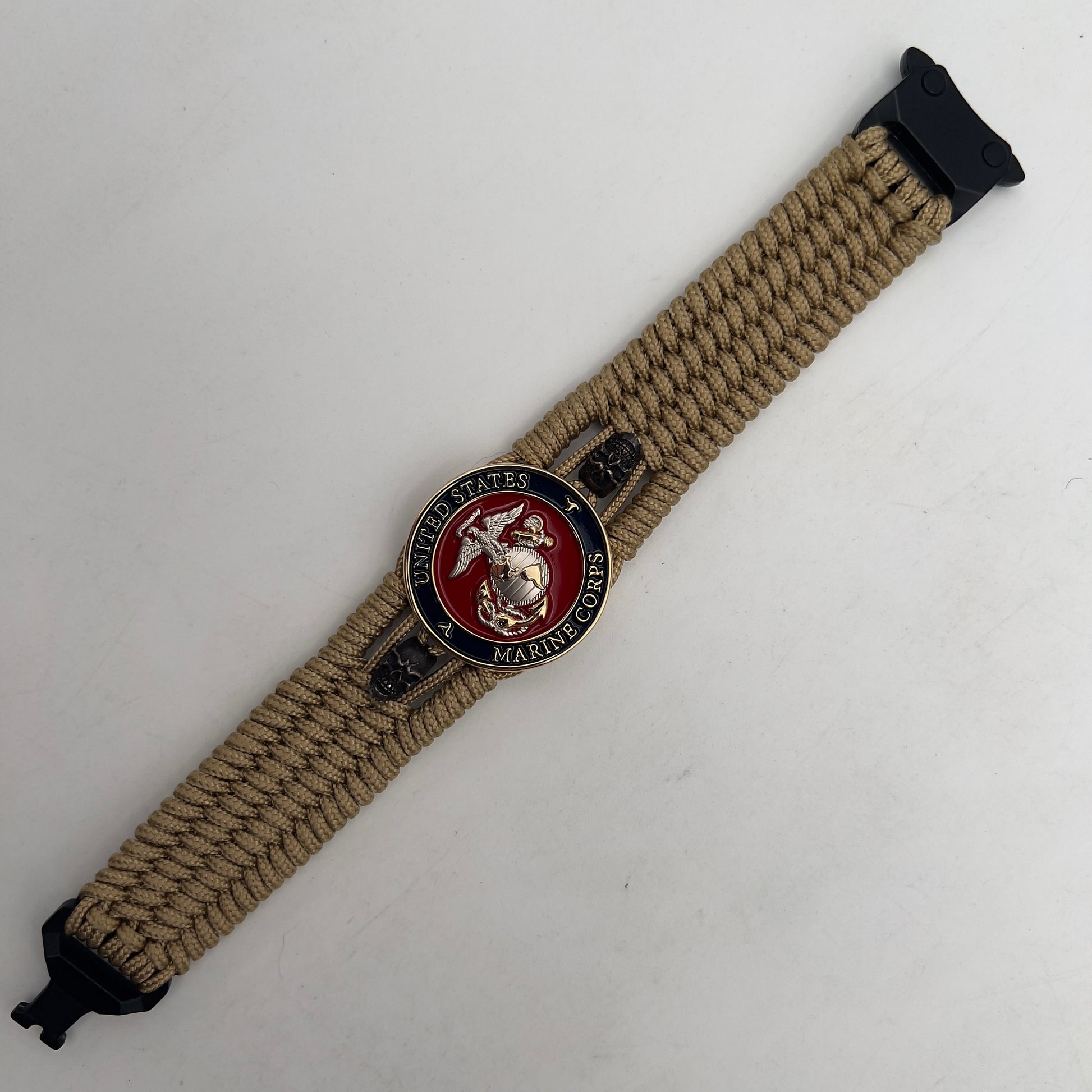 Thin, medium width, flexible and comfortable braided United States Marine Corps bracelet featuring a 24K gold and silver plated USMC officer Eagle Globe and Anchor medallion, two black micro skulls, a black Cobra style tactical buckle and woven with gold type-1 paracord.