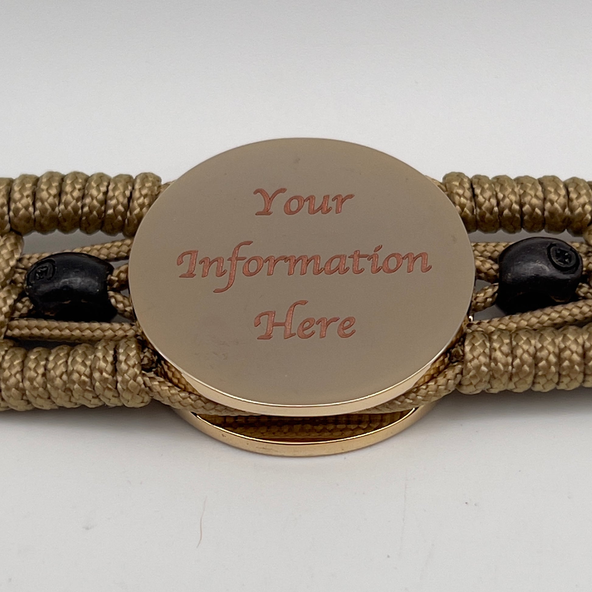 Thin, medium width, flexible and comfortable braided United States Marine Corps bracelet featuring a 24K gold and silver plated USMC officer Eagle Globe and Anchor medallion, two black micro skulls, a black Cobra style tactical buckle and woven with gold type-1 paracord.