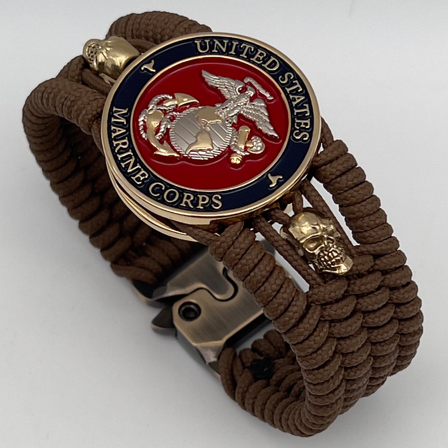 Thin, medium width, flexible and comfortable braided United States Marine Corps bracelet featuring a 24K gold and silver plated USMC officer Eagle Globe and Anchor medallion, two gold micro skulls, a gold Cobra style tactical buckle and woven with Coyote Brown type-1 paracord.