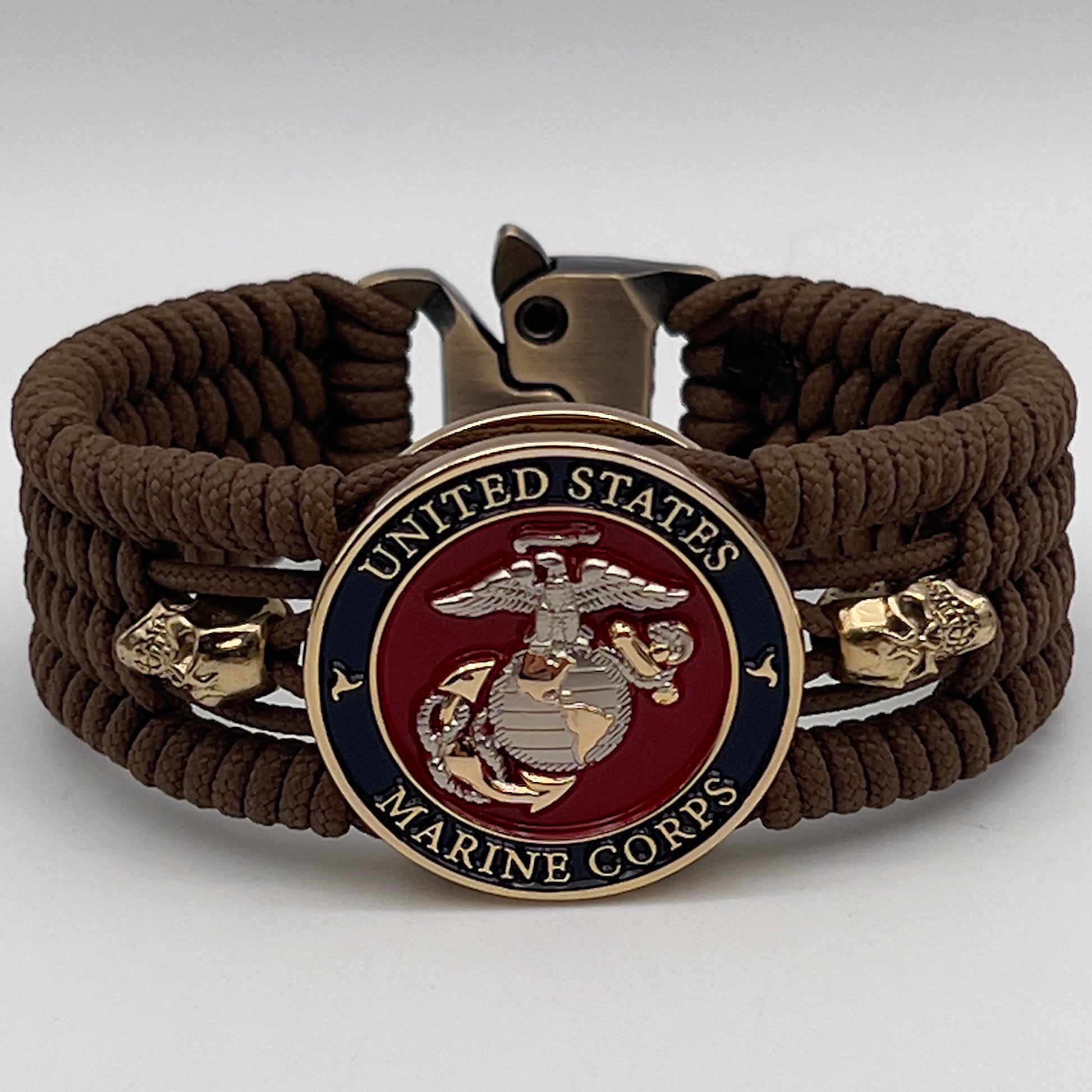 Thin, medium width, flexible and comfortable braided United States Marine Corps bracelet featuring a 24K gold and silver plated USMC officer Eagle Globe and Anchor medallion, two gold micro skulls, a gold Cobra style tactical buckle and woven with Coyote Brown type-1 paracord.