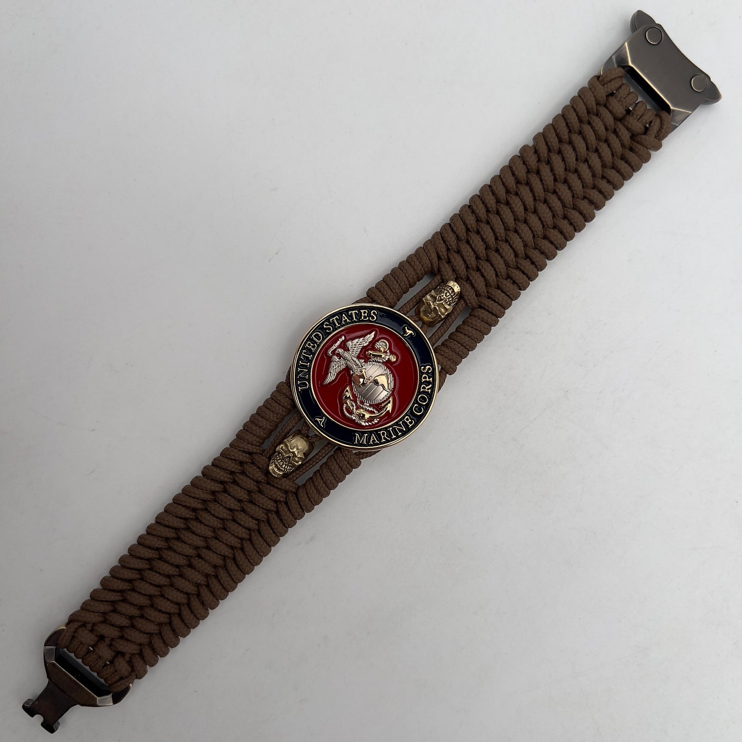 Thin, medium width, flexible and comfortable braided United States Marine Corps bracelet featuring a 24K gold and silver plated USMC officer Eagle Globe and Anchor medallion, two gold micro skulls, a gold Cobra style tactical buckle and woven with Coyote Brown type-1 paracord.