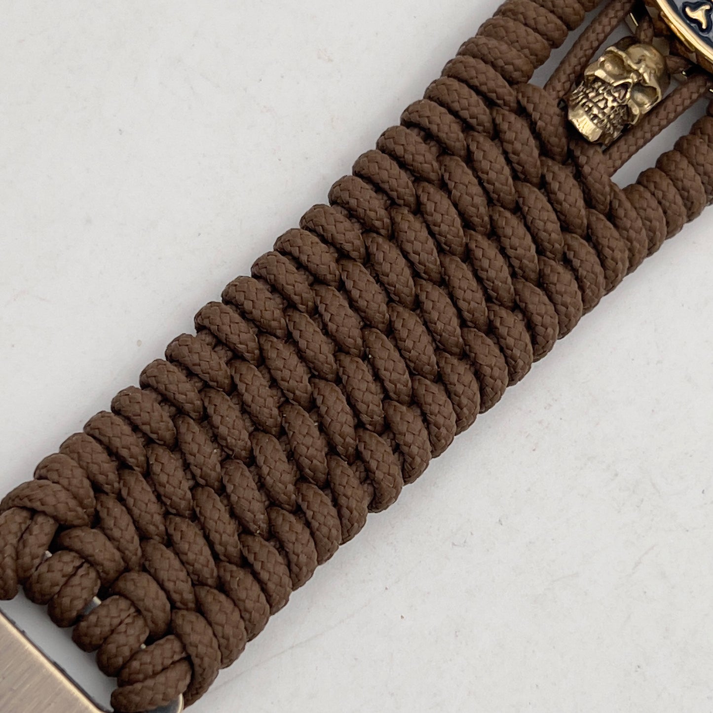 Thin, medium width, flexible and comfortable braided United States Marine Corps bracelet featuring a 24K gold and silver plated USMC officer Eagle Globe and Anchor medallion, two gold micro skulls, a gold Cobra style tactical buckle and woven with Coyote Brown type-1 paracord.