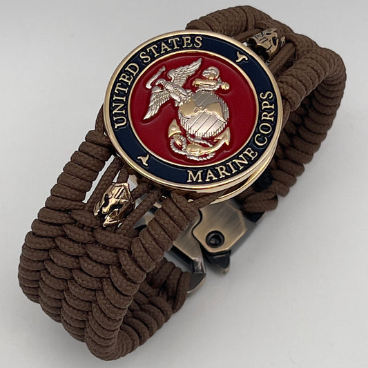 Thin, medium width, flexible and comfortable braided United States Marine Corps bracelet featuring a 24K gold and silver plated USMC officer Eagle Globe and Anchor medallion, two brass micro Spartan helmets, a gold Cobra style tactical buckle and woven with Coyote Brown type-1 paracord.