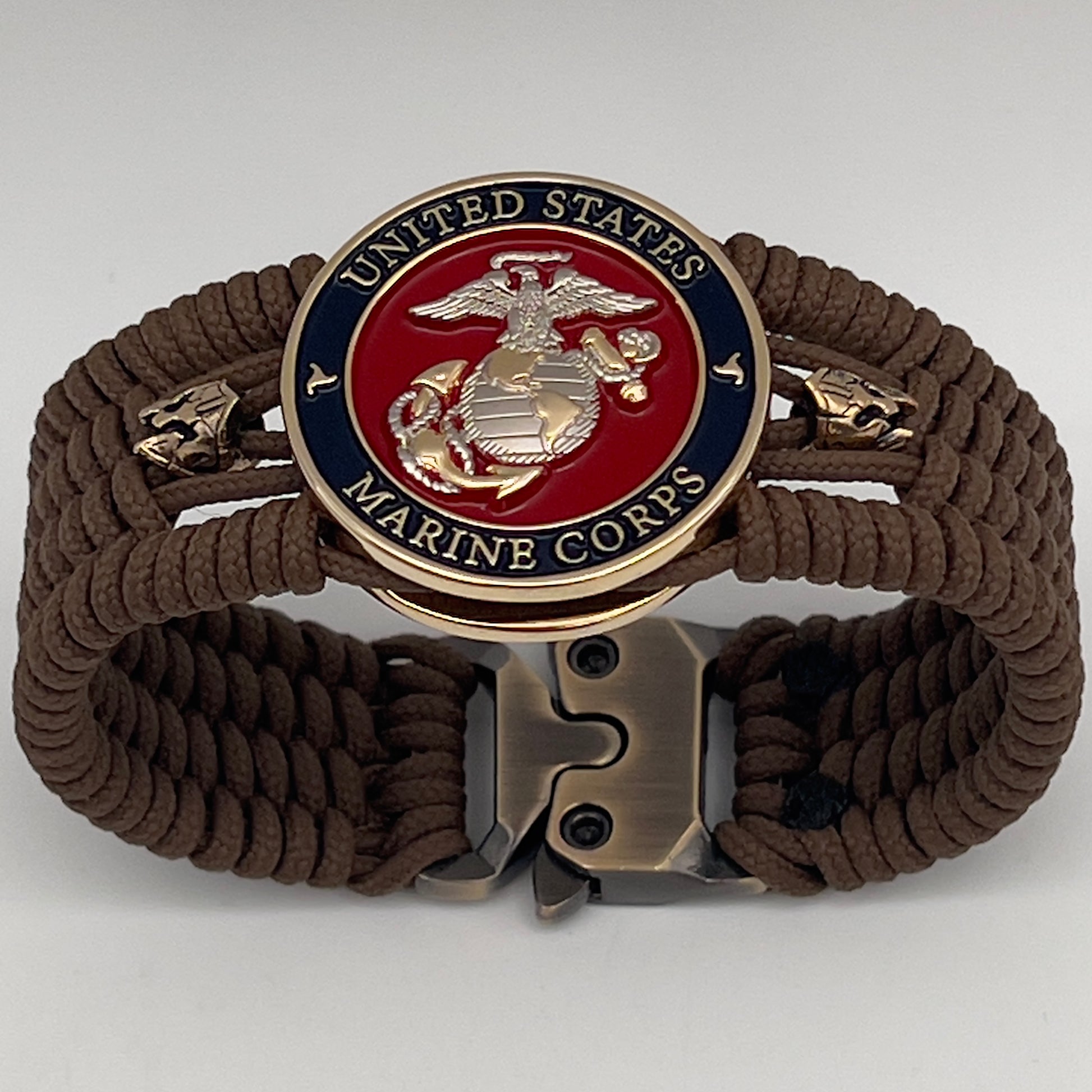 Thin, medium width, flexible and comfortable braided United States Marine Corps bracelet featuring a 24K gold and silver plated USMC officer Eagle Globe and Anchor medallion, two brass micro Spartan helmets, a gold Cobra style tactical buckle and woven with Coyote Brown type-1 paracord.
